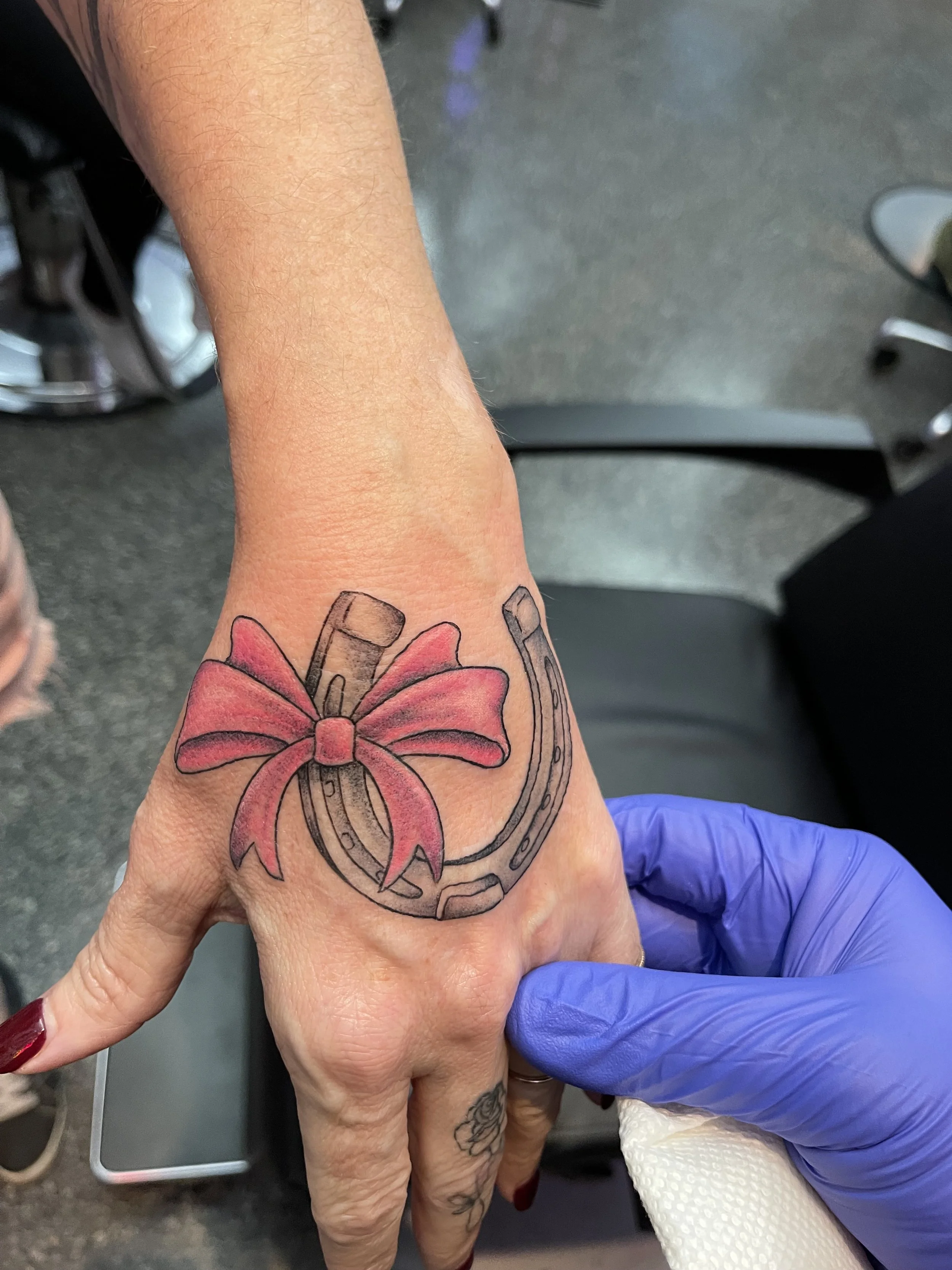 bow on horseshoe hand tattoo.jpeg