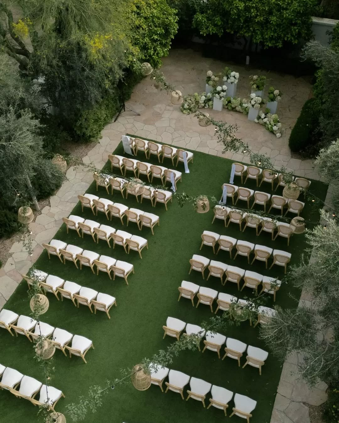 Our Sofia Chairs set up for a ceremony at @elchorroweddings, all neutral tones, woven lanterns lining the aisle, and that gorgeous hydrangea altar framed by some of the best greenery in the Valley. The cane back on the Sofia was made for a dreamy set