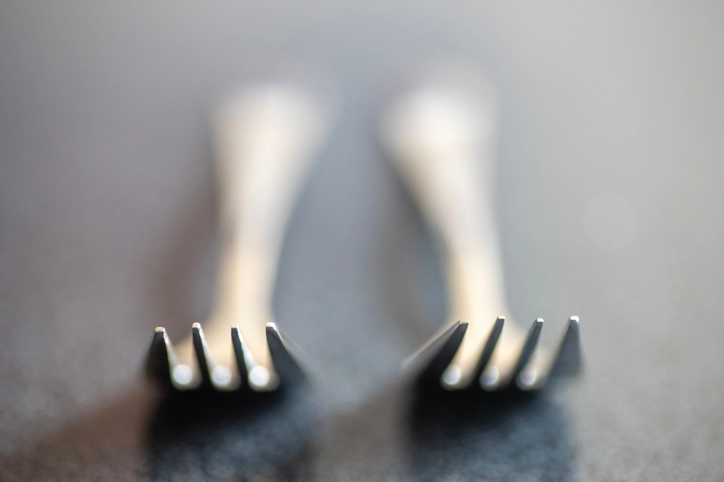 two silver forks on counter with blurred background