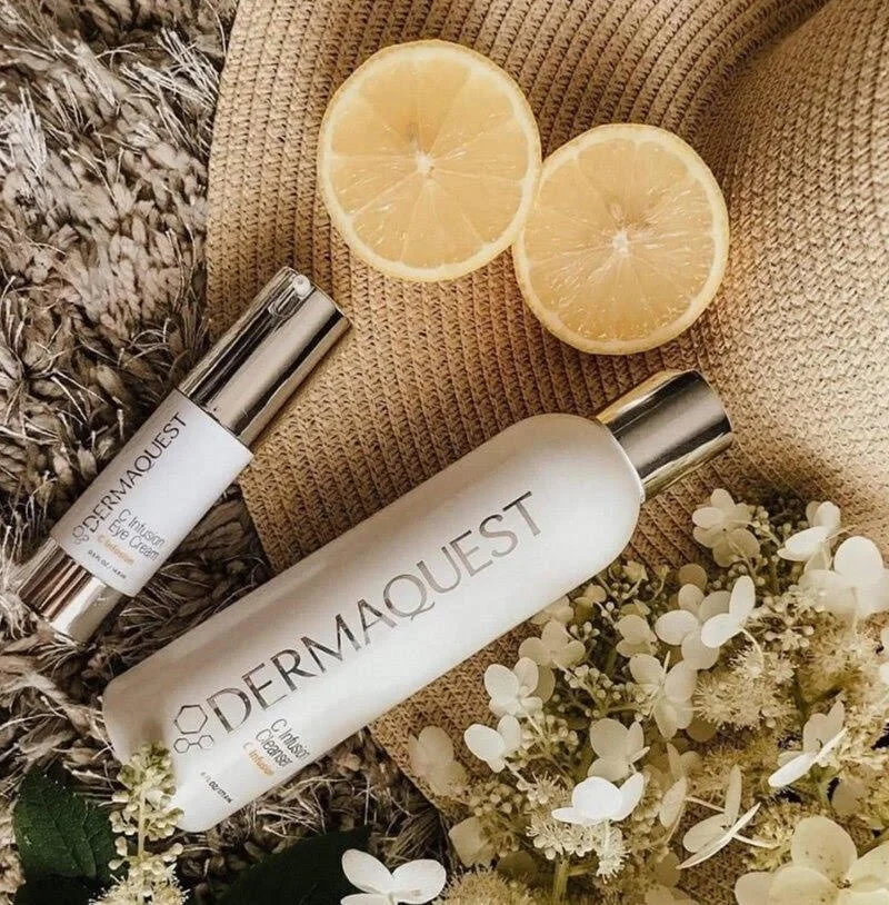 Skincare products from Dermaquest, lemon halves, white flowers, and textured fabric background.