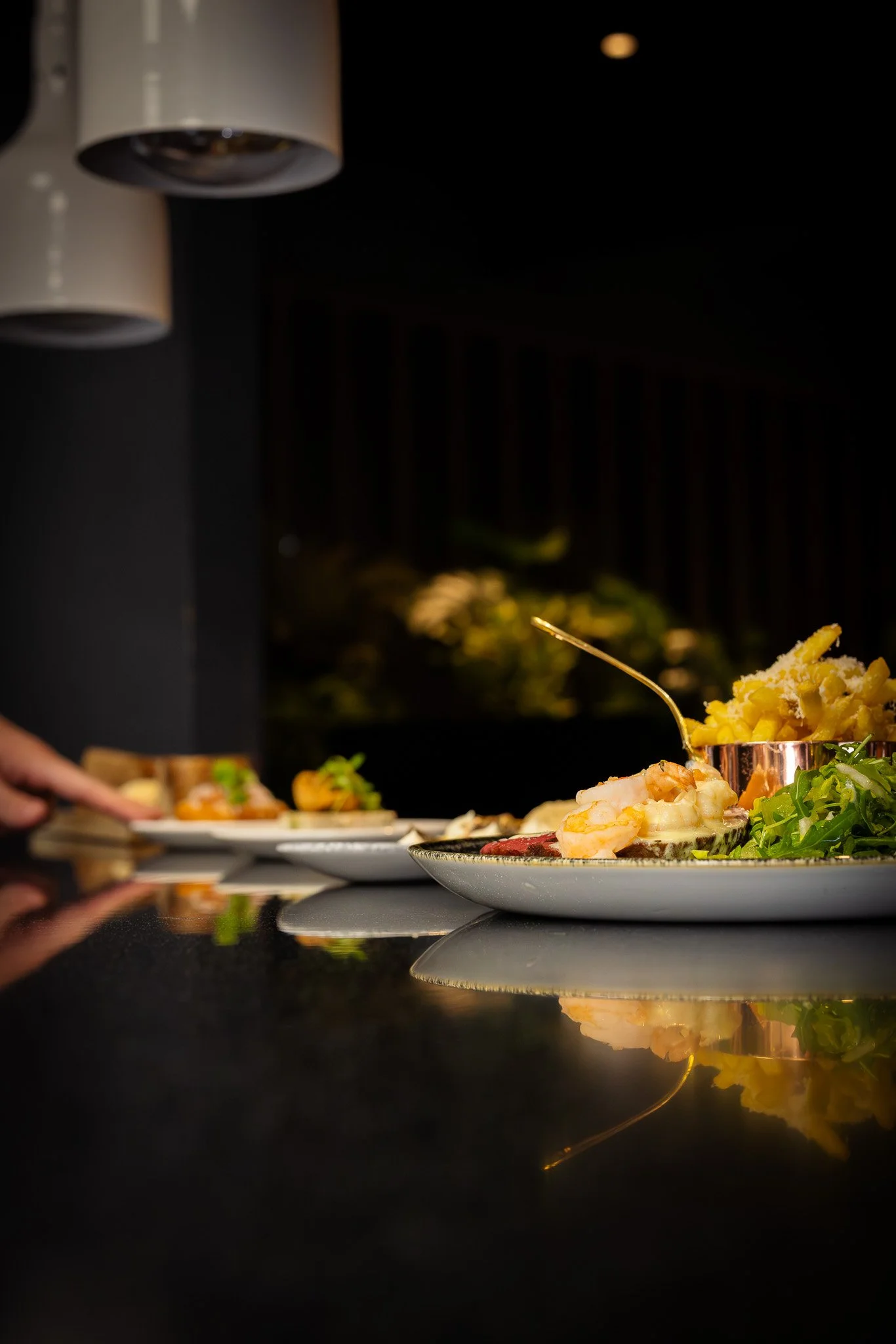 Close-up of plates with food on a black counter at a restaurant, with blurred background.
