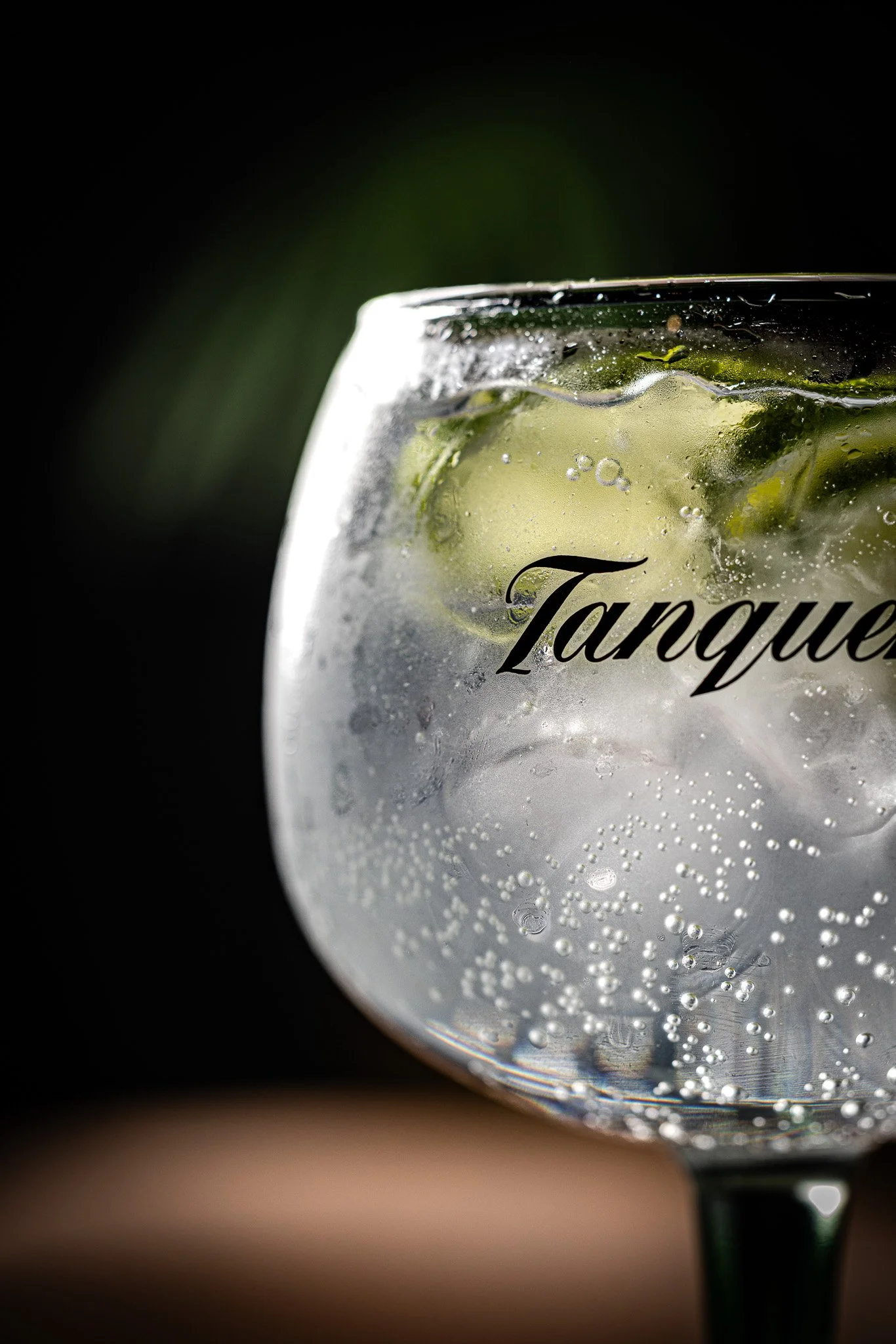 Close-up of a glass of tonic water with lime slices and bubbles, against a dark background.