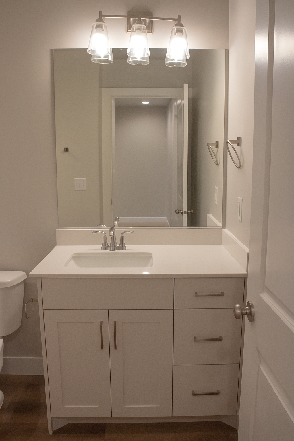 Contemporary walk-in shower enclosure with a sliding glass door and chrome frame. The interior features light gray subway tile walls, a built-in corner bench for seating, and a wall-mounted chrome towel bar.