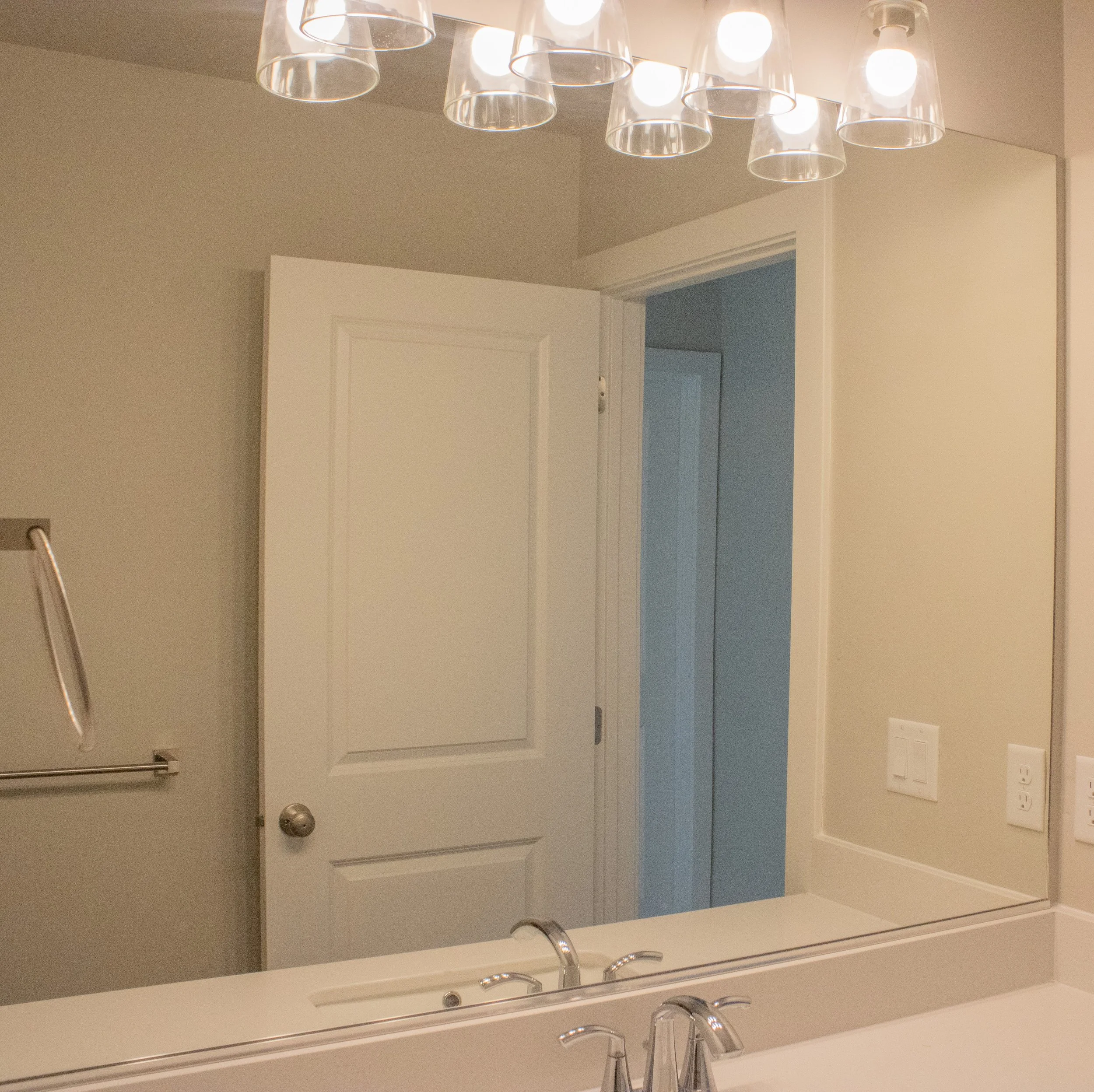 Stylish residential bathroom vanity with ample counter space, a large rectangular mirror, and modern, linear lighting fixtures.