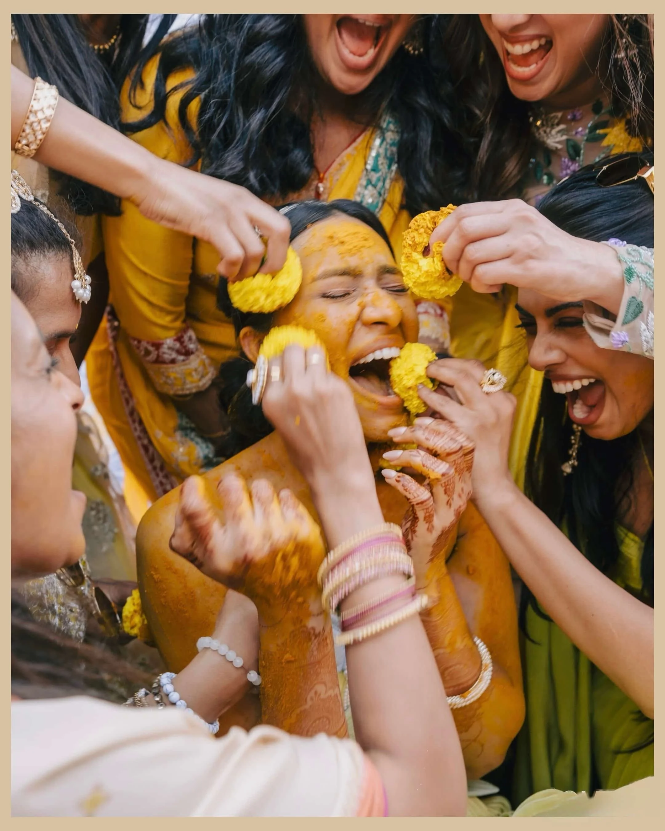Women participating in a traditional Indian pre-wedding ceremony, applying turmeric paste on the bride's face.