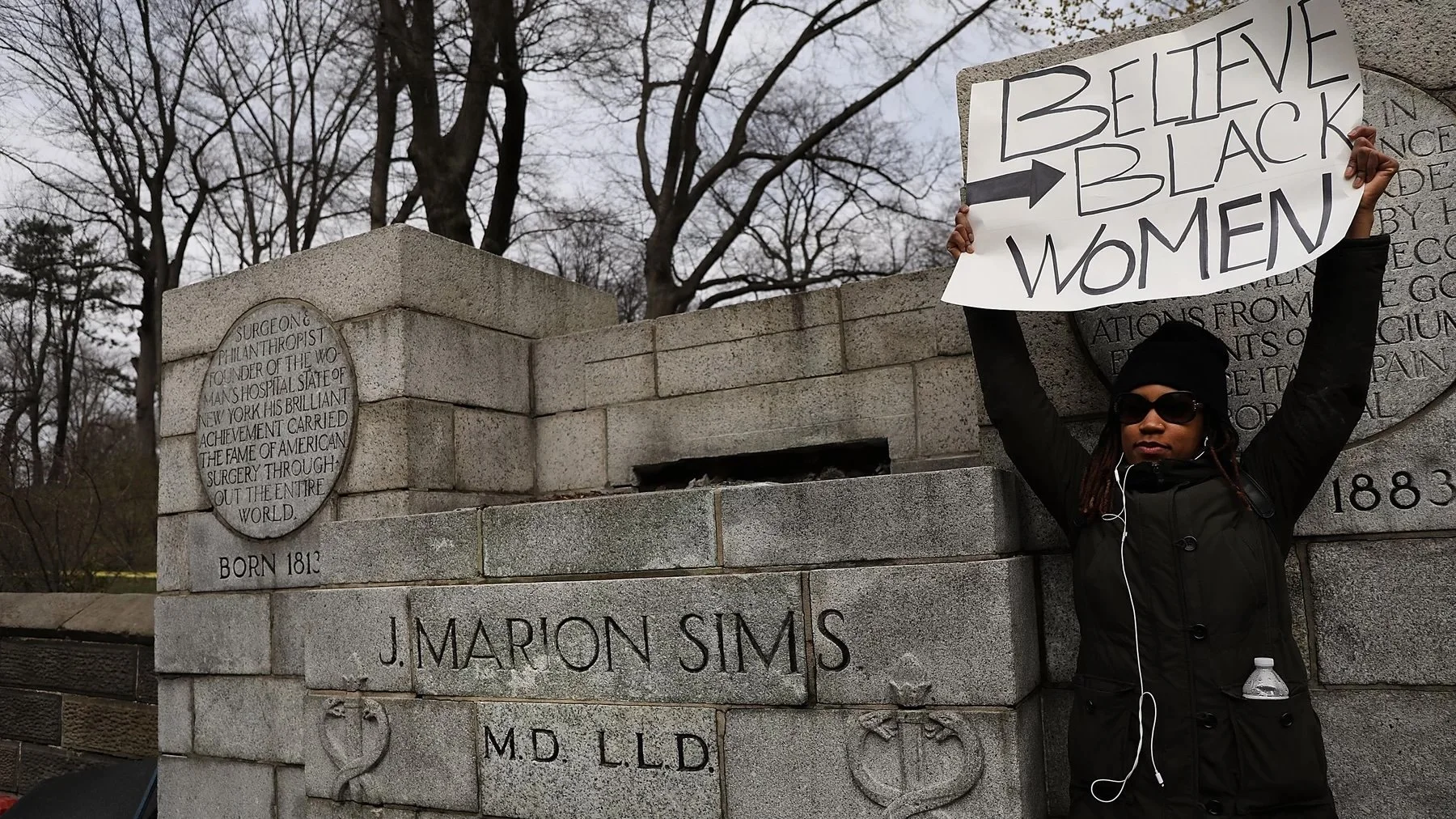 Woman beside empty pedestal where statue of Dr. J. Marion Sims used to stand