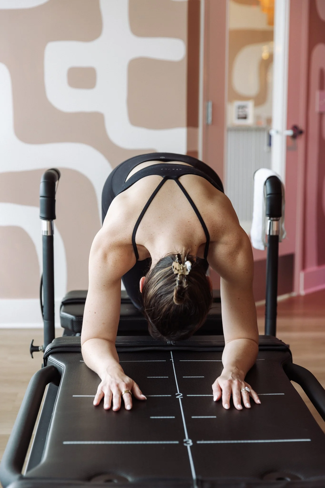 Reformer Pilates machines in a fitness studio with mirrors and pink walls.