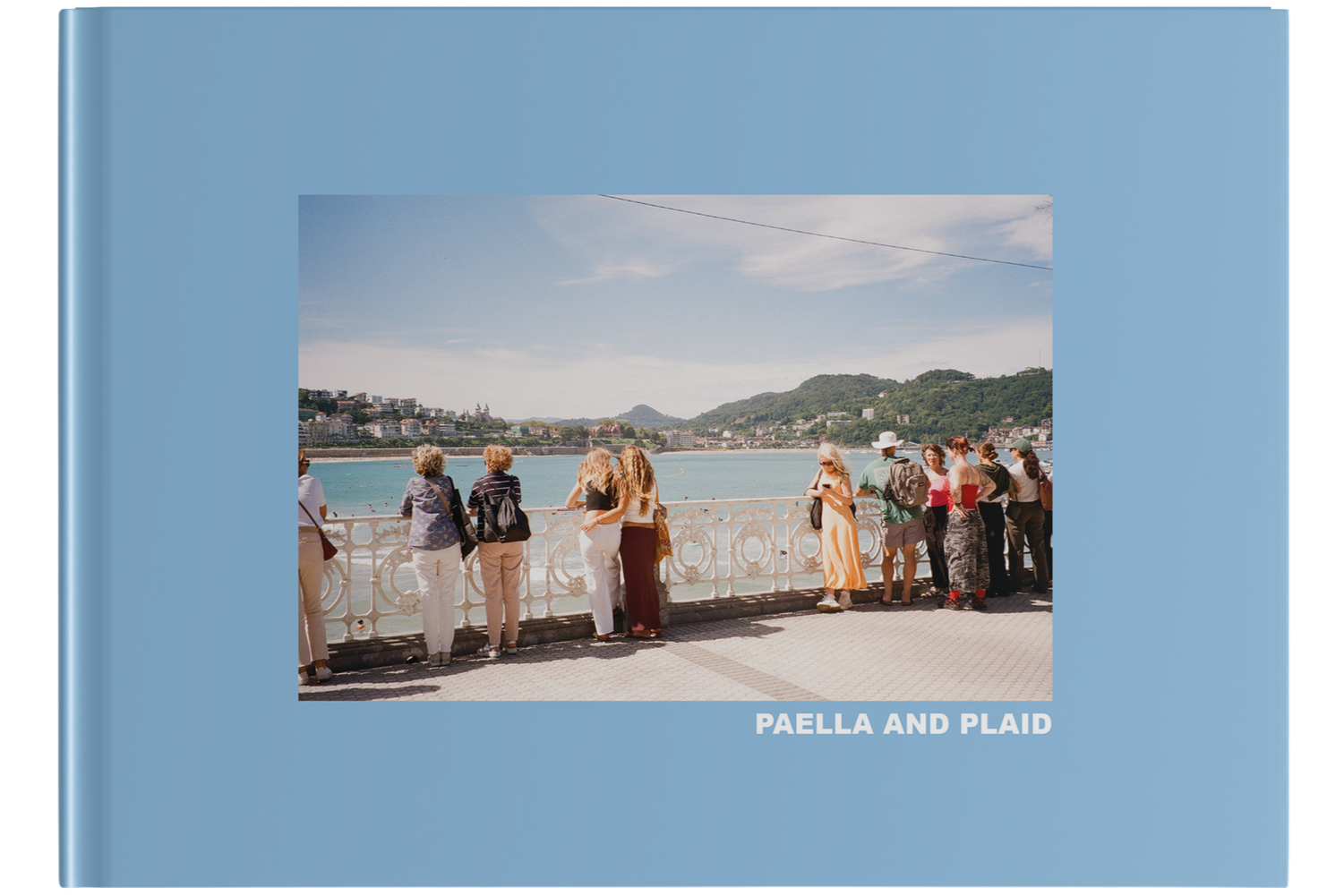 Blue book cover with a photograph of people standing by a river with a city and mountains in the background. The title 'PAELLA AND PLAID' is in white uppercase letters at the bottom of the cover.