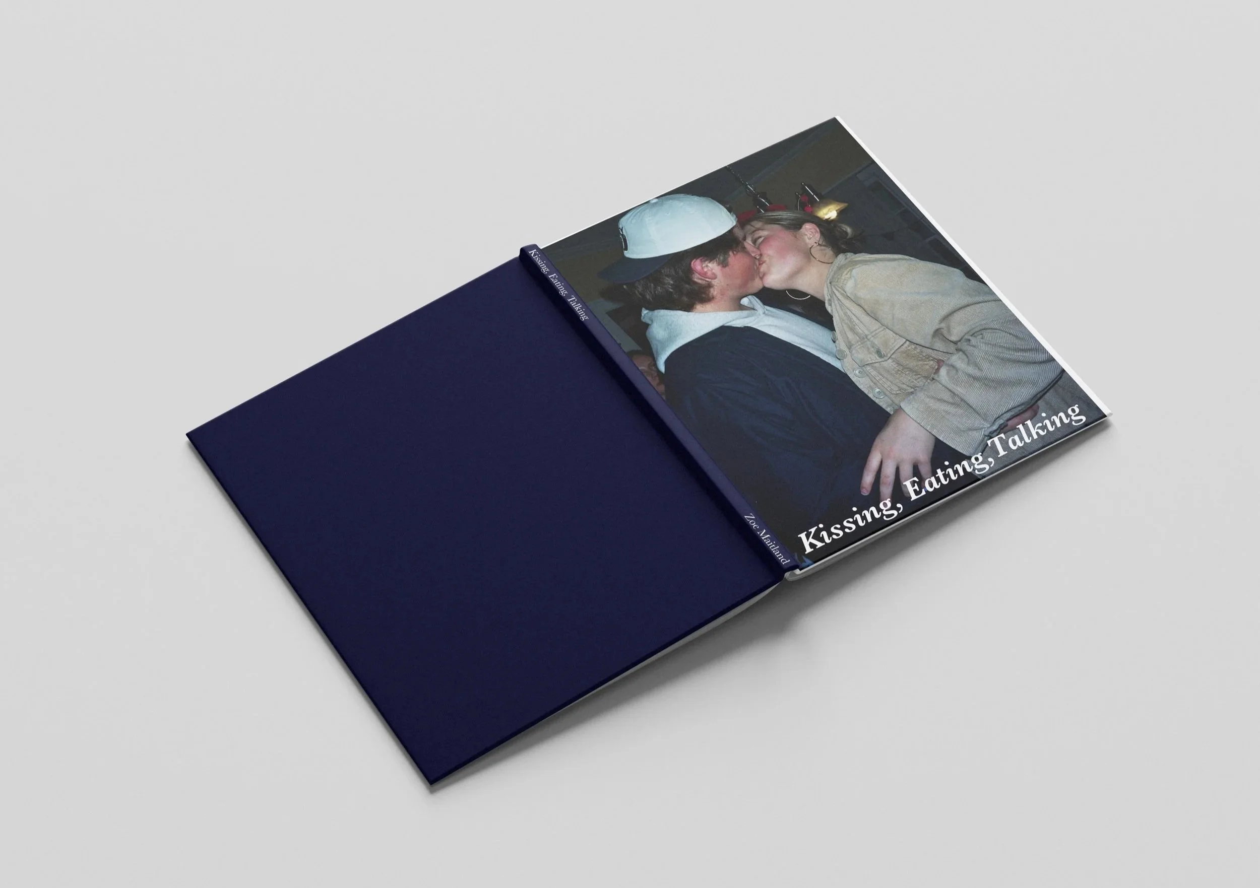 A photo book open to a picture of a couple kissing, with the title 'Kissing, Eating, Talking' on the cover.