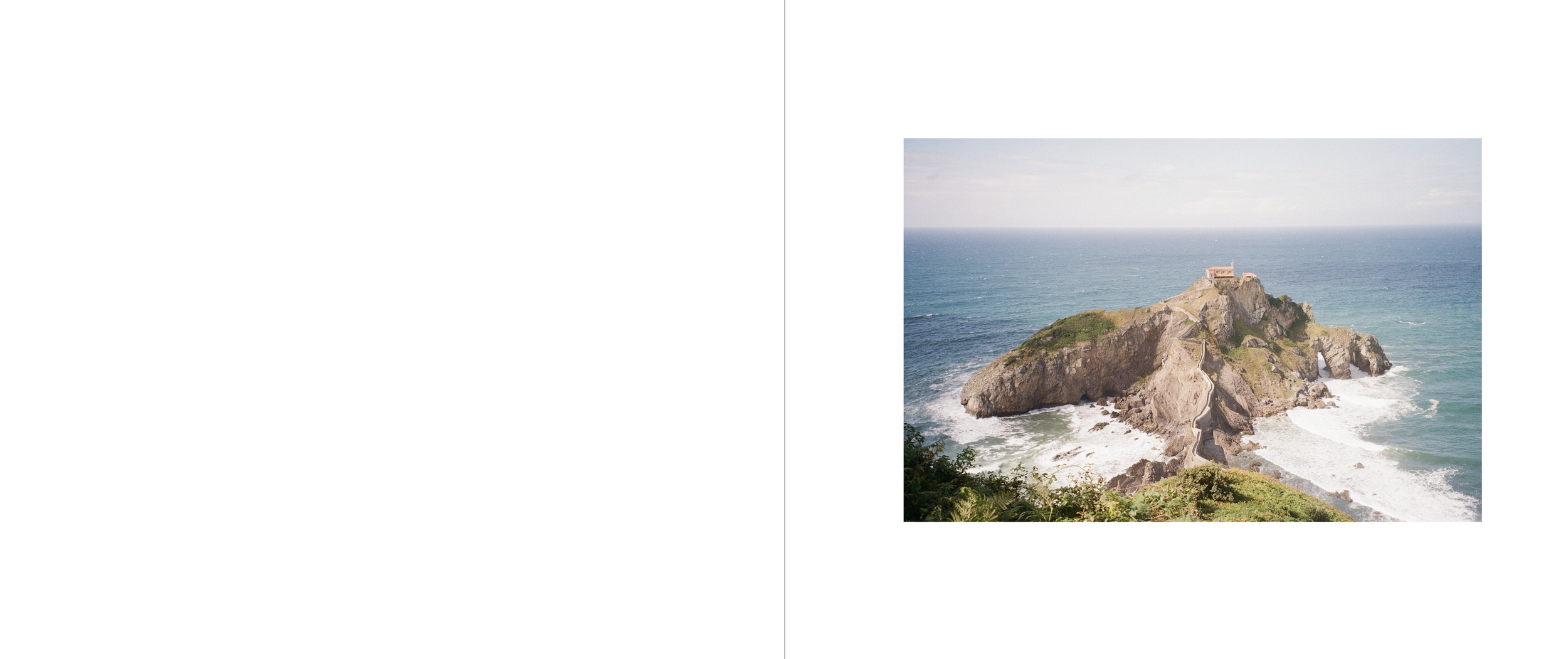 A rocky island with a small building at the top, surrounded by ocean waves and a distant sky.