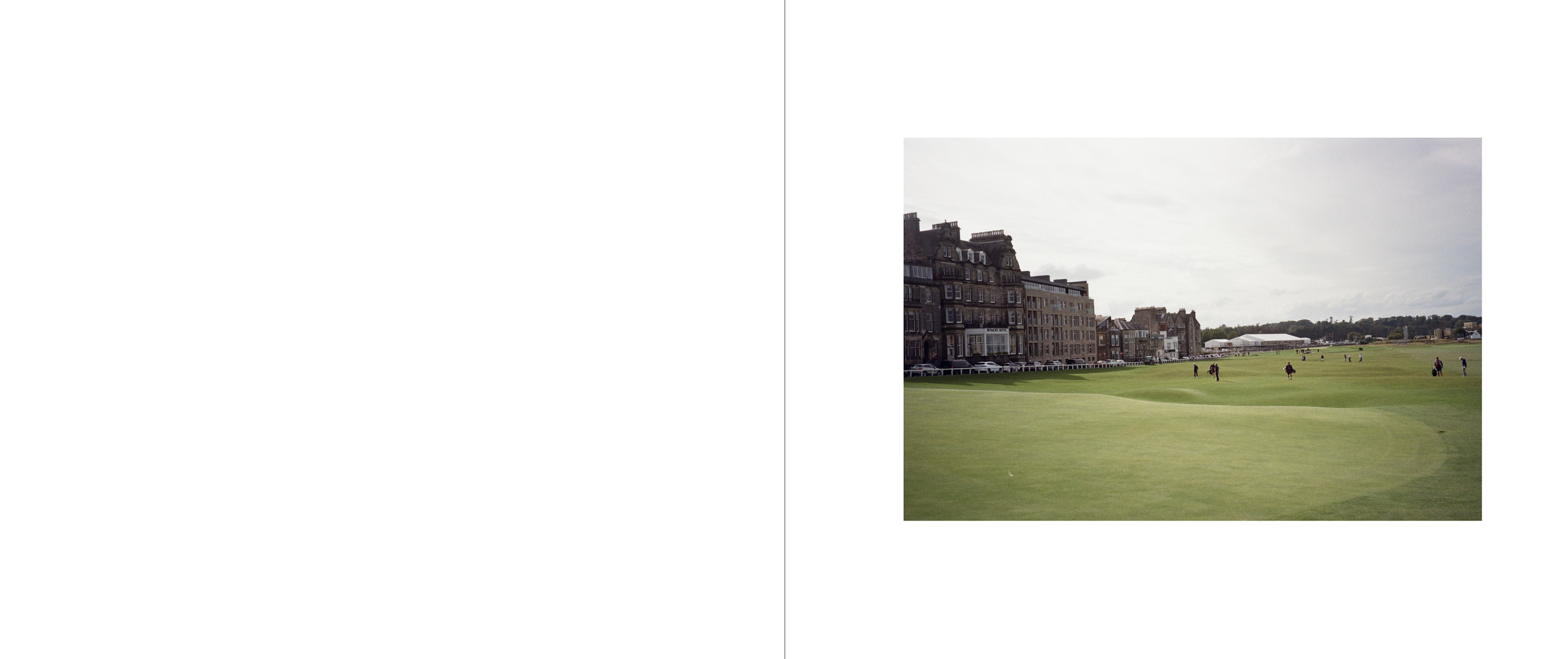 A golf course with people playing golf, bordered by multi-story buildings and parked cars, under an overcast sky.