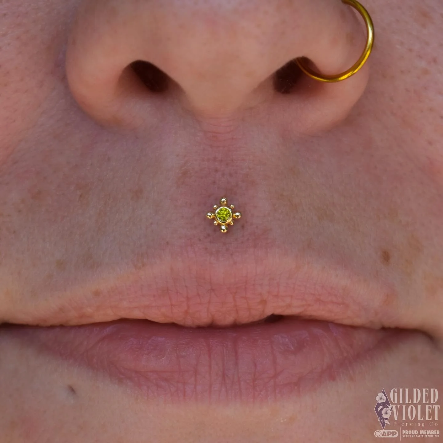 Olive green cz + yellow gold Bindi for this fresh philtrum, just l o o k at that glow! ✨
 Samantha asked for dainty, but bold- and this piece was the obvious choice 🫒

#gildedvioletpiercing #fiveoneseventattoo #jeannettepa #philtrumpiercing #medusap