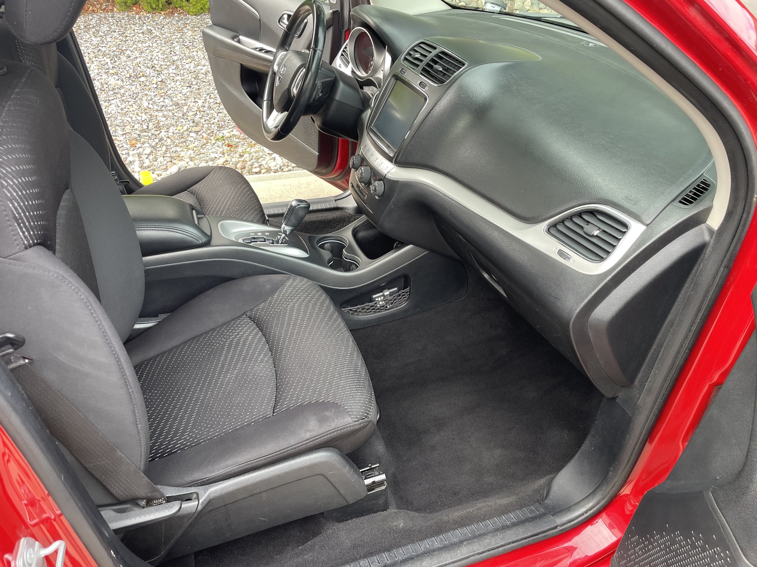 Interior of a parked red car showing driver's seat, dashboard, and center console.