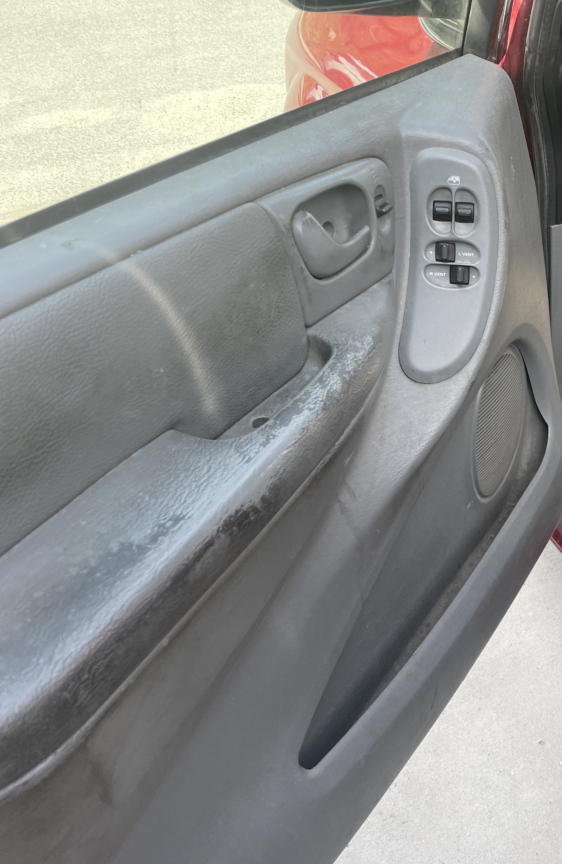 Interior of a car door with power window controls and armrest.
