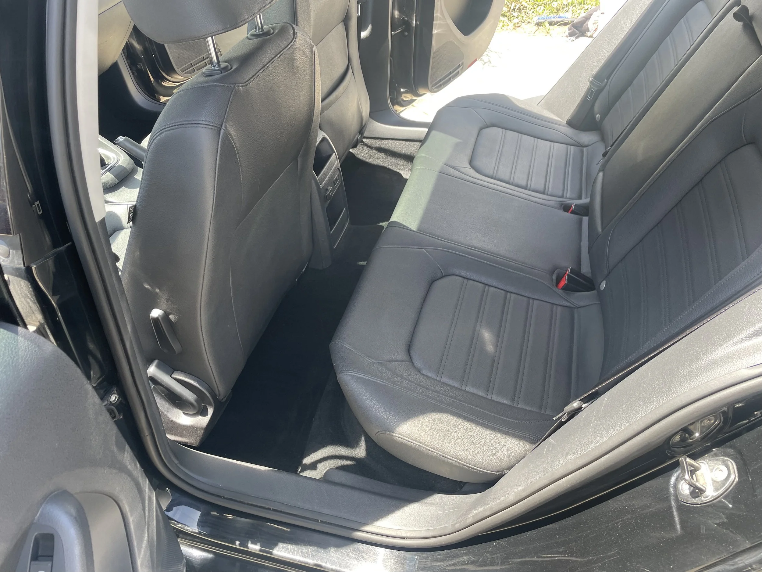 interior of a car, back seat view, leather seats, open rear door