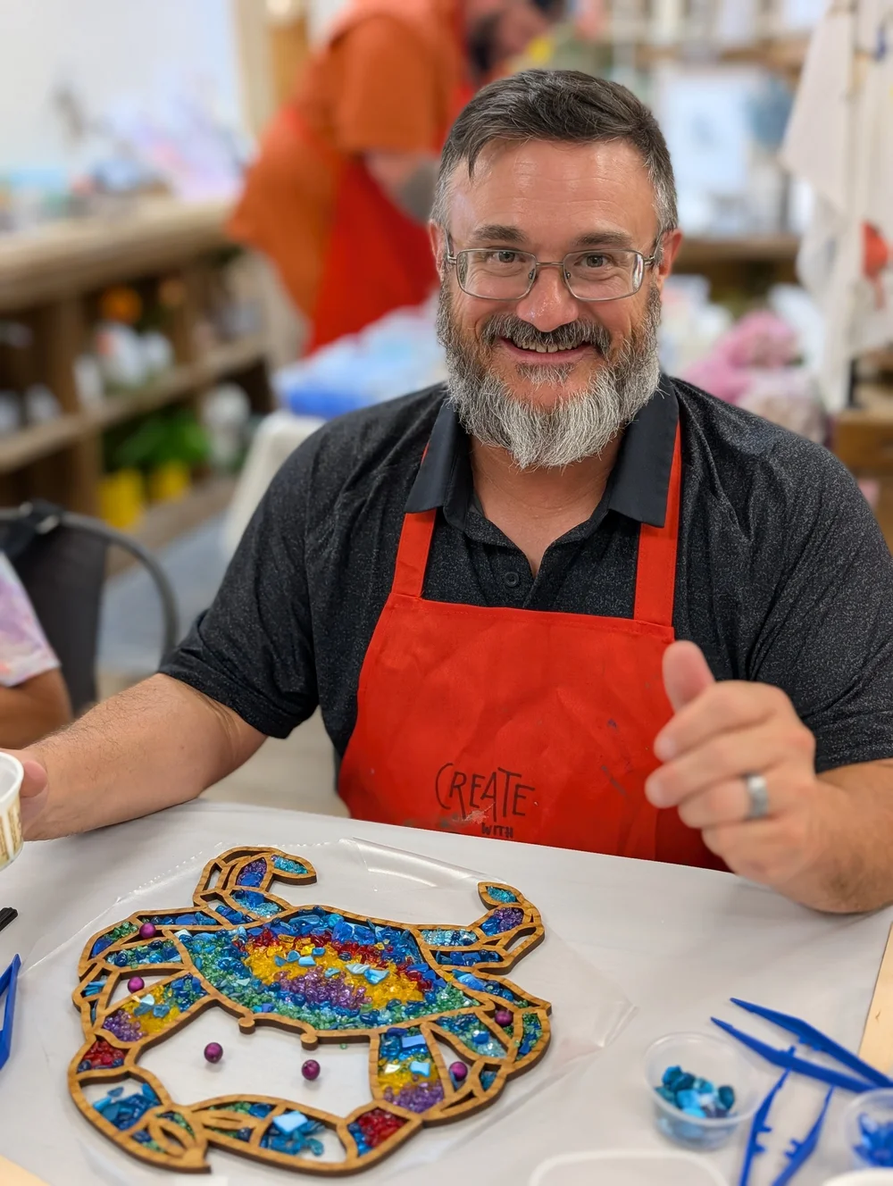 A participant proudly creating a colorful crushed glass project