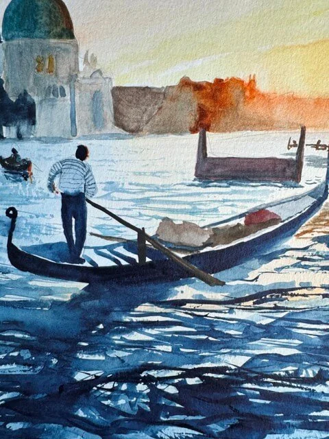 Closeup of a gondolier standing on his gondola, with rippling blue water beneath him