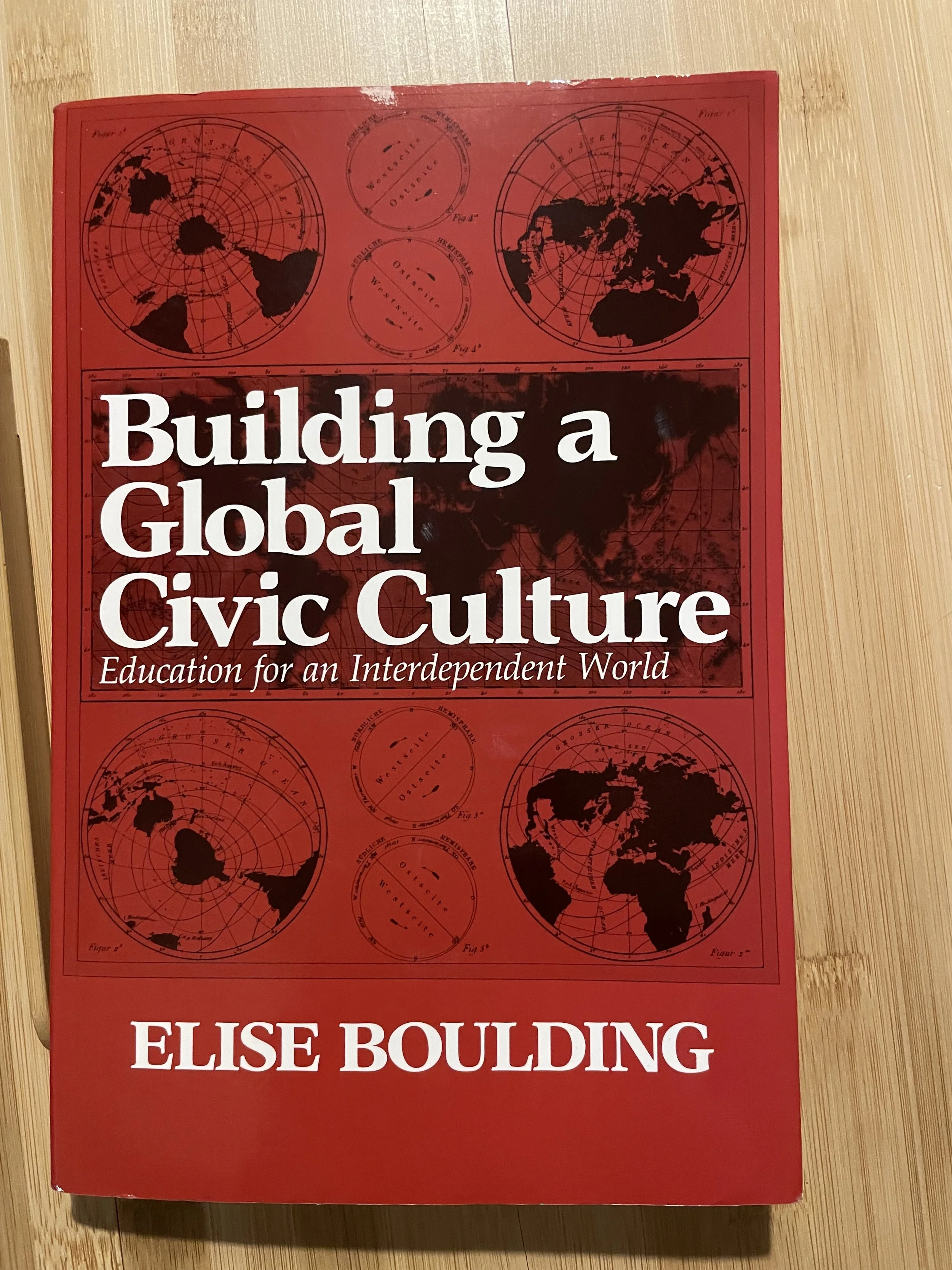 Red book titled 'Building a Global Civic Culture' by Elise Boulding with a background of world maps and globes.