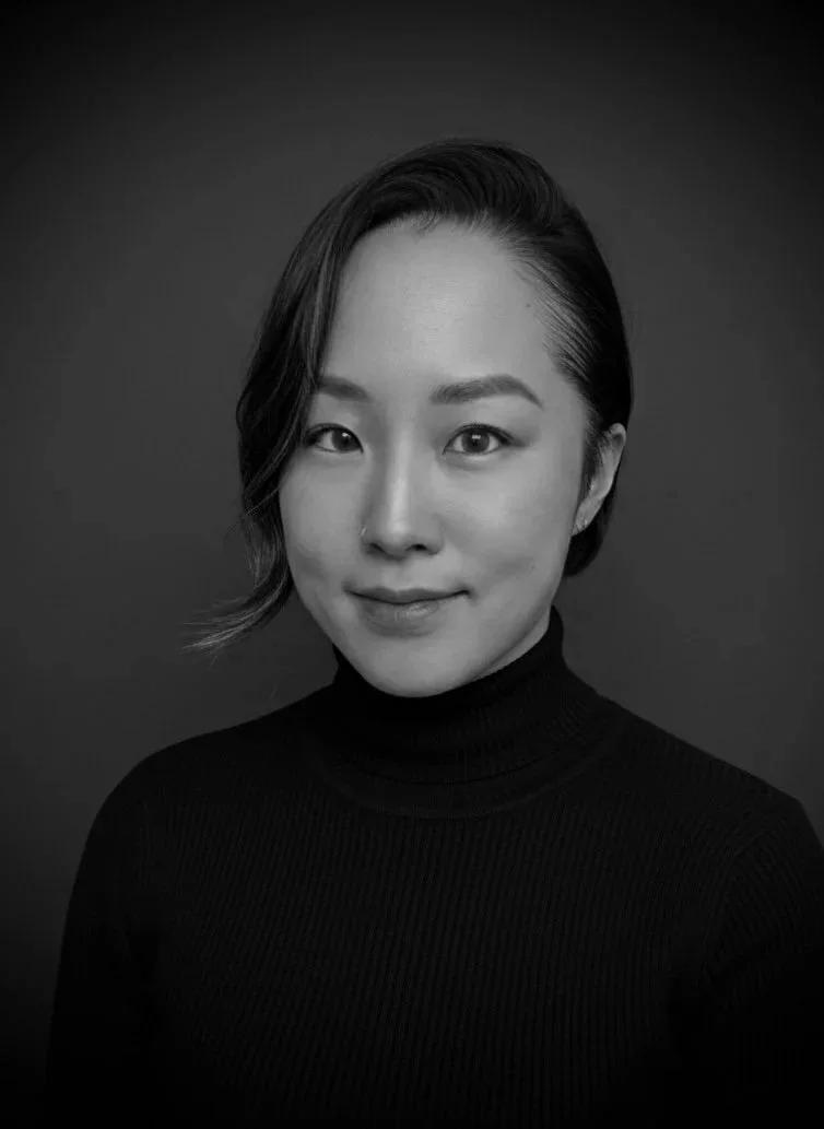 Black and white portrait of a woman with short hair, wearing a black turtleneck, looking at the camera with a slight smile.