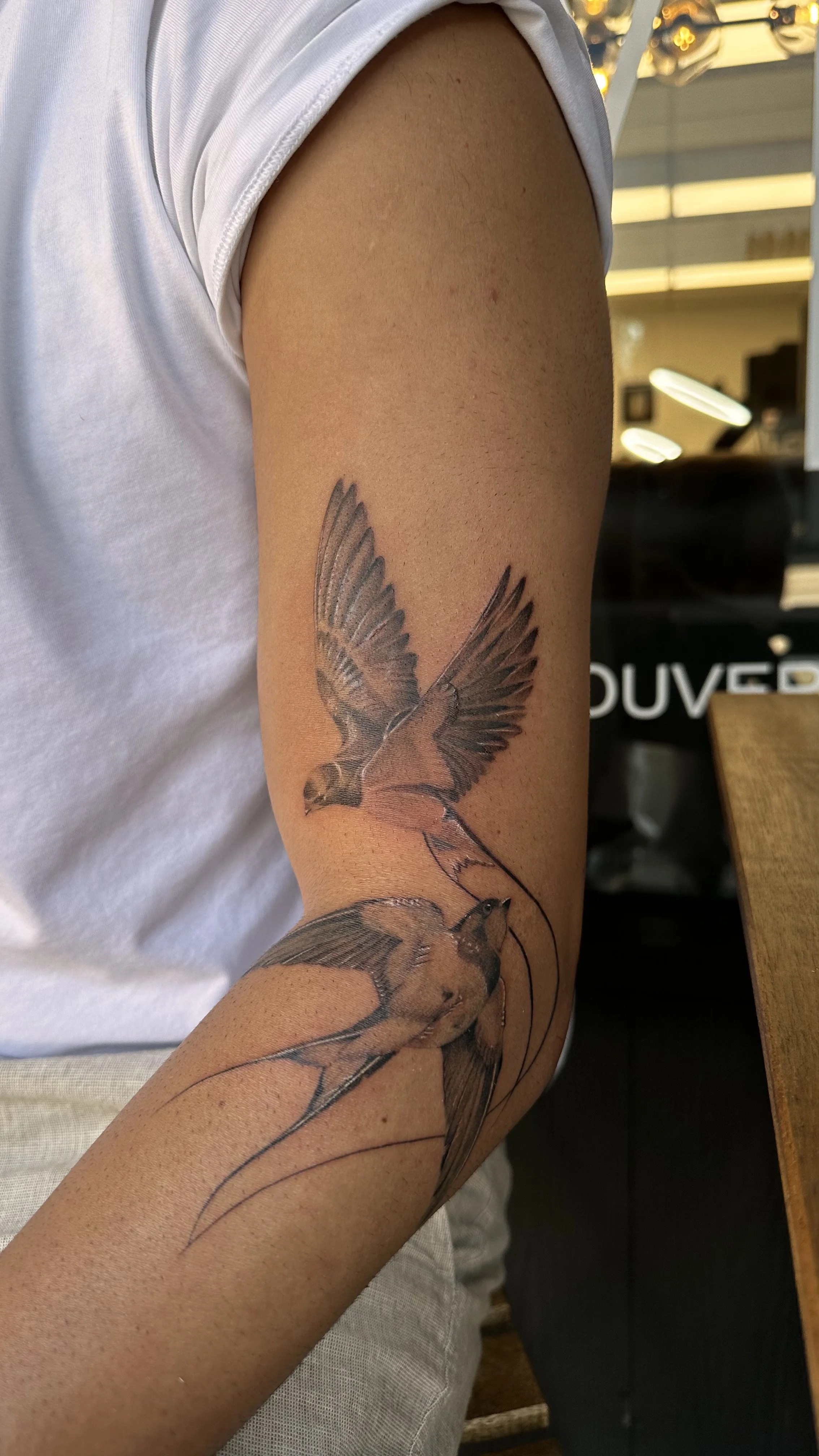 Tattoo of birds flying on a person's upper arm.