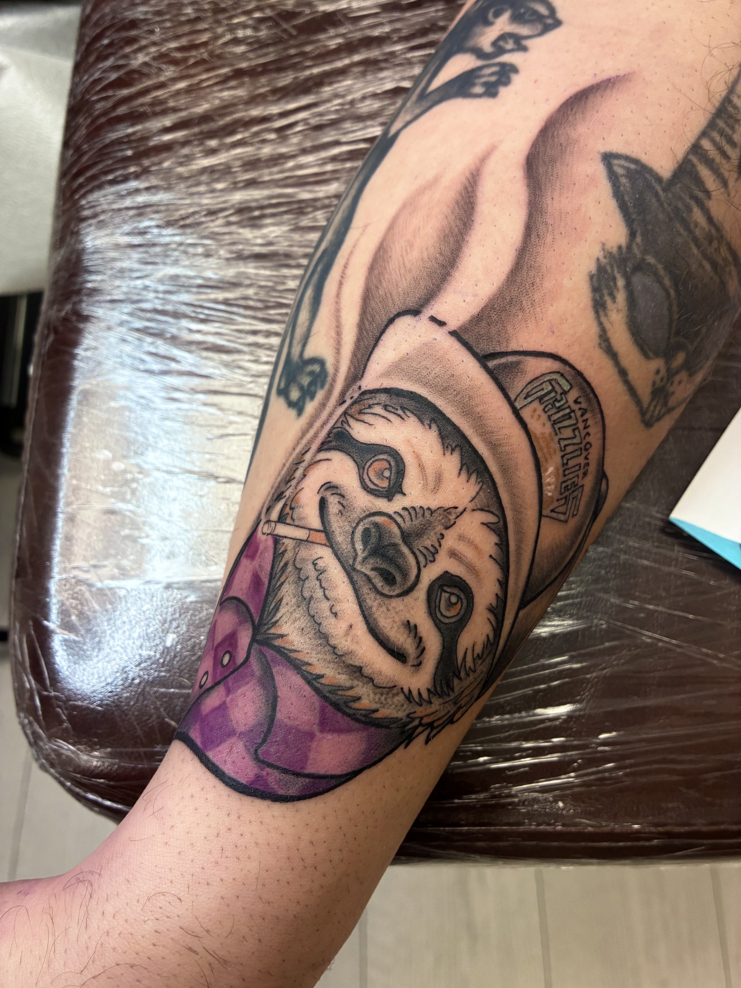 A tattoo of a cartoon bear holding a microphone, with text that reads 'FIGHT CLUB' and 'LOS ANGELES' on the arm.