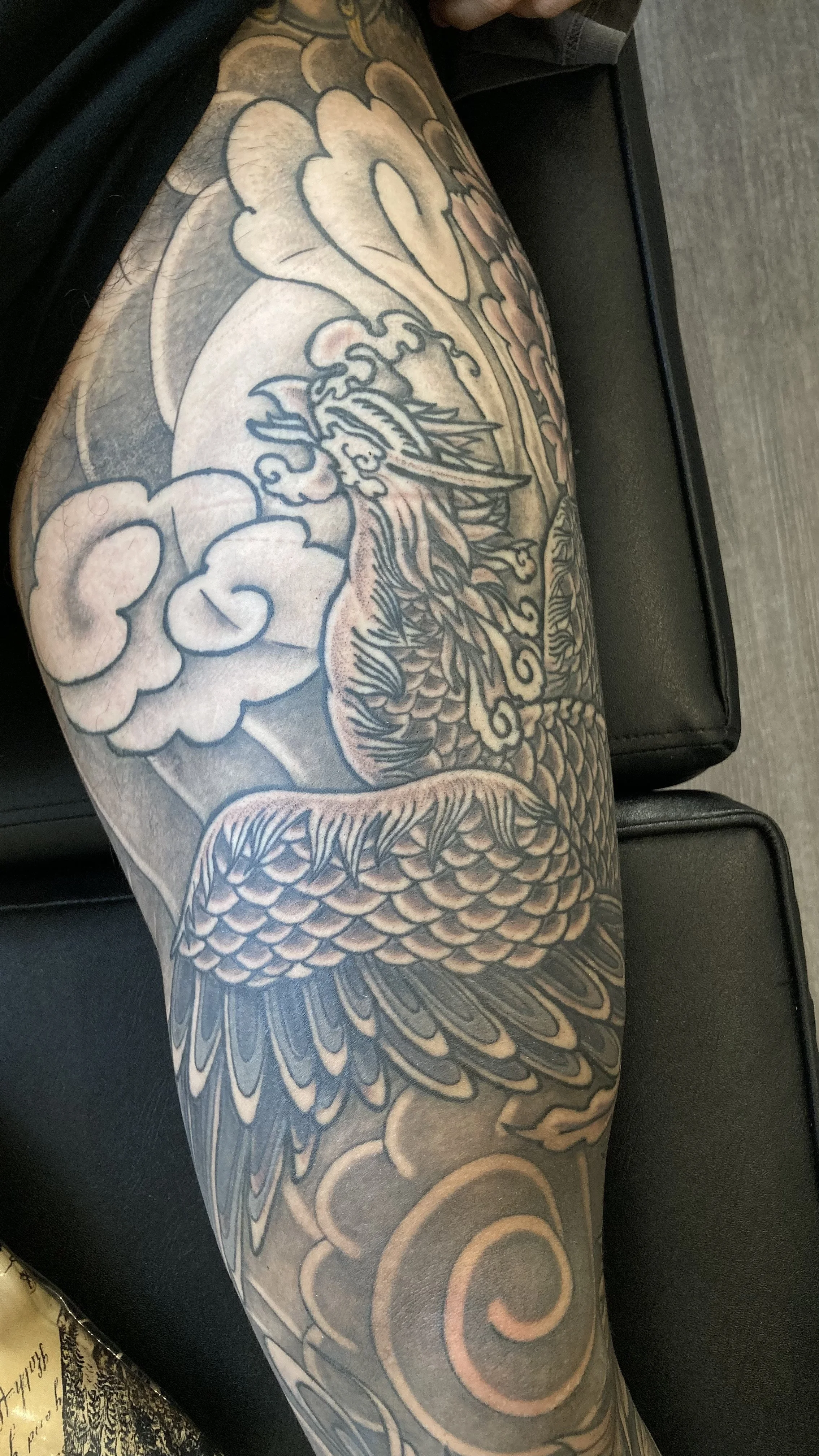 Black and gray tattoo of a dragon with detailed scales on a person's arm.