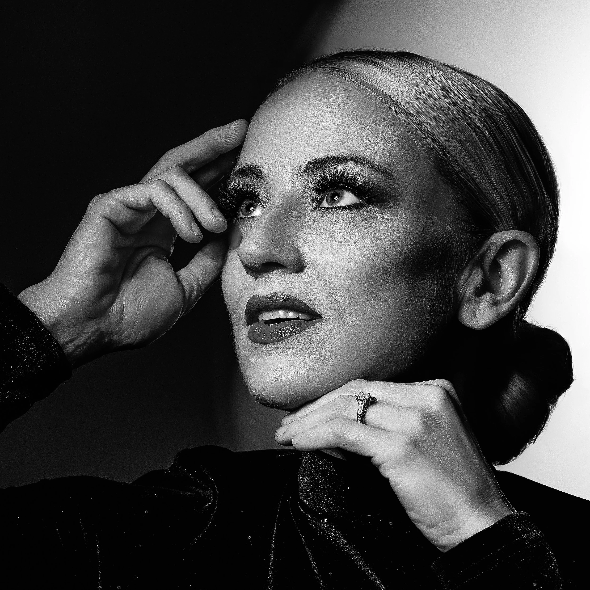 Black-and-white creative portrait of a blonde woman looking upward with dramatic studio lighting
