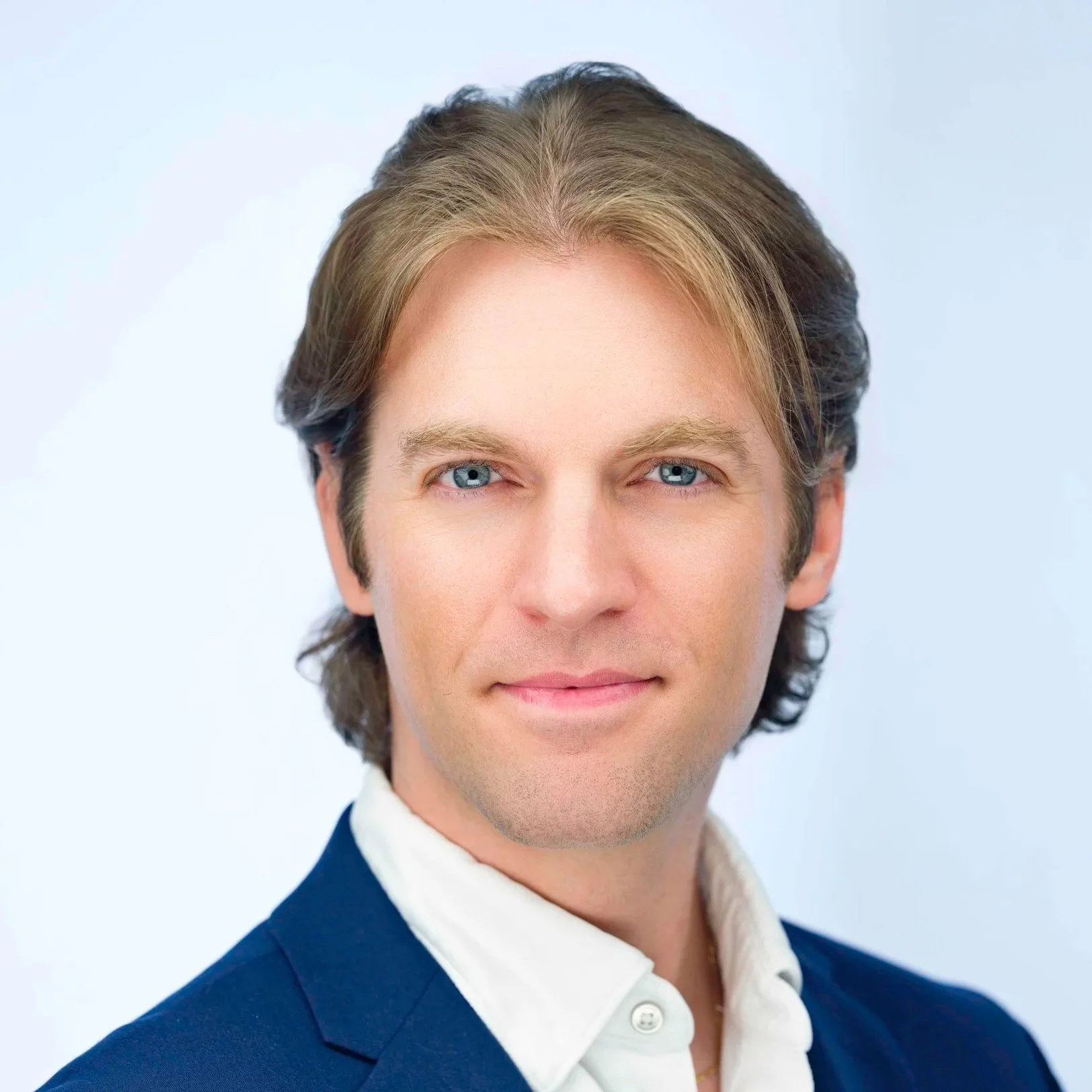 Professional headshot of a man in a blue jacket against a clean white background