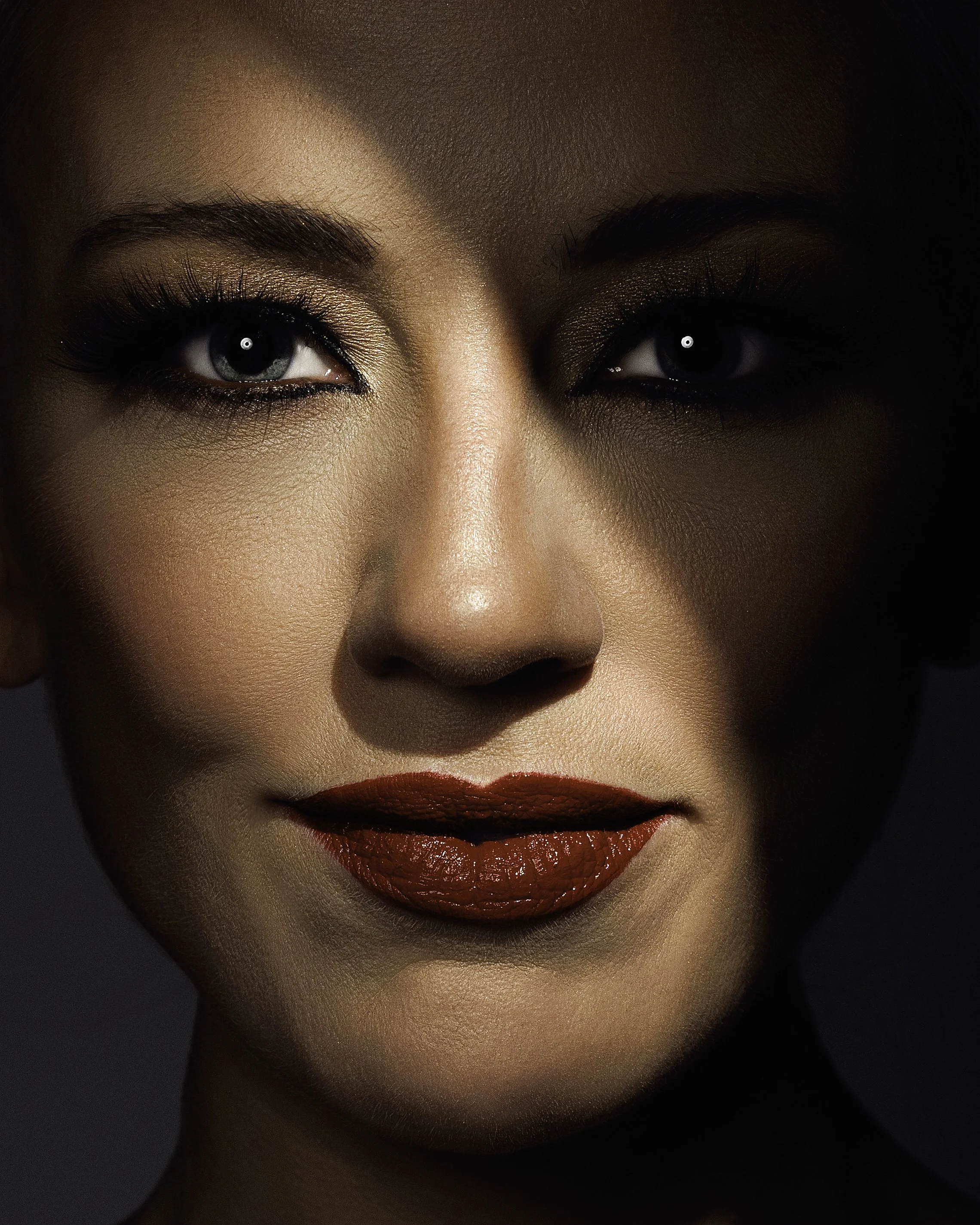 Close-up creative beauty portrait of a blonde woman with red lipstick and dramatic studio lighting