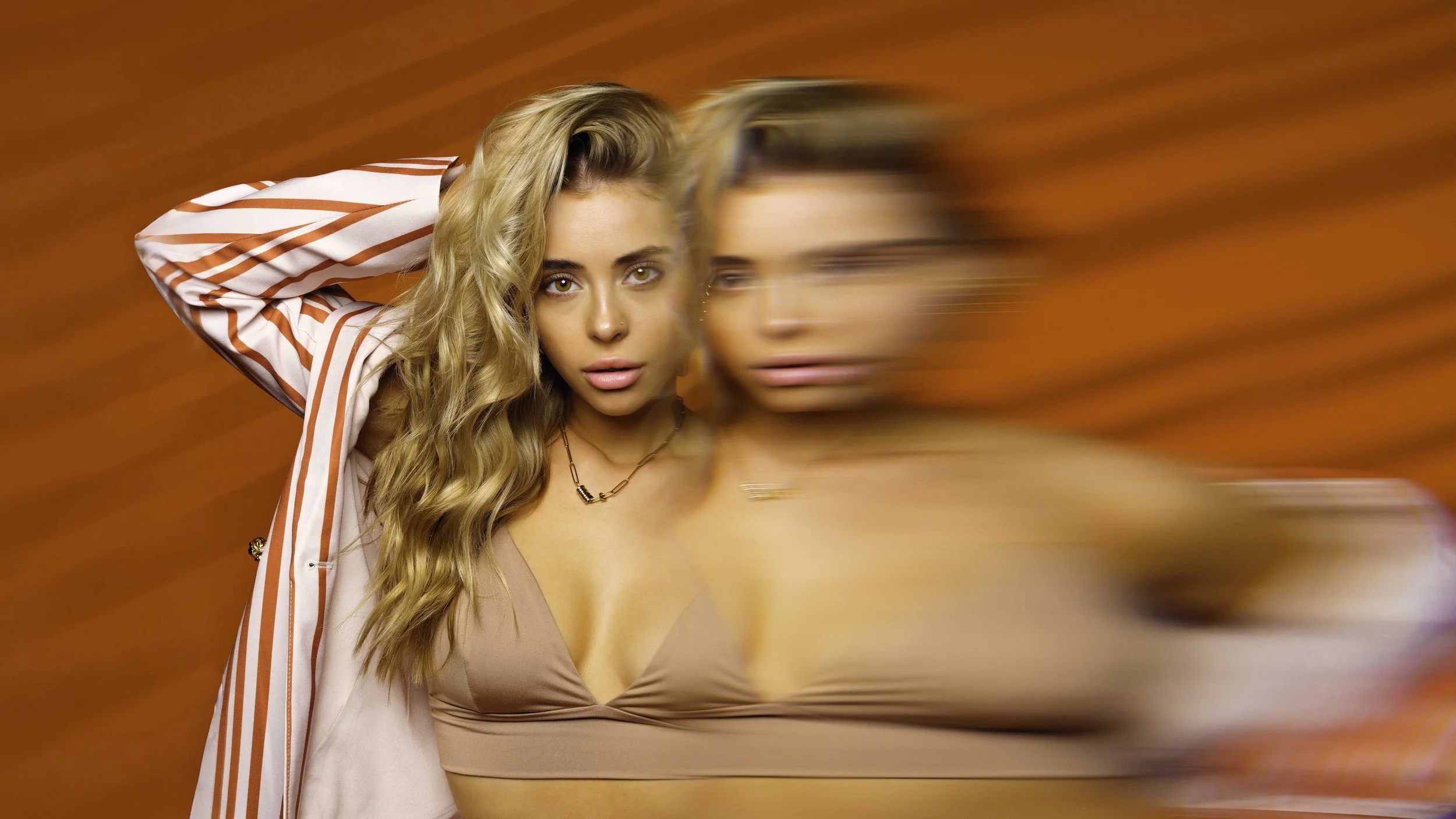 Creative portrait of a blonde woman using intentional motion blur against an orange background