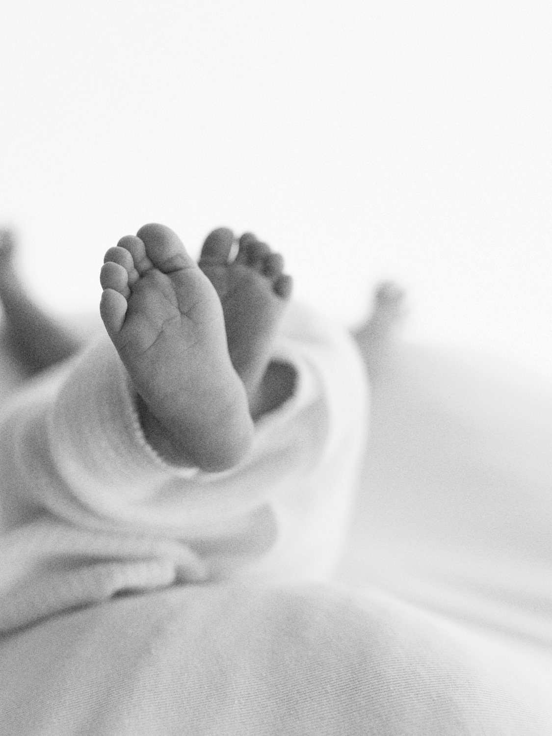 Close-up of baby feet in soft focus, wearing light clothing.