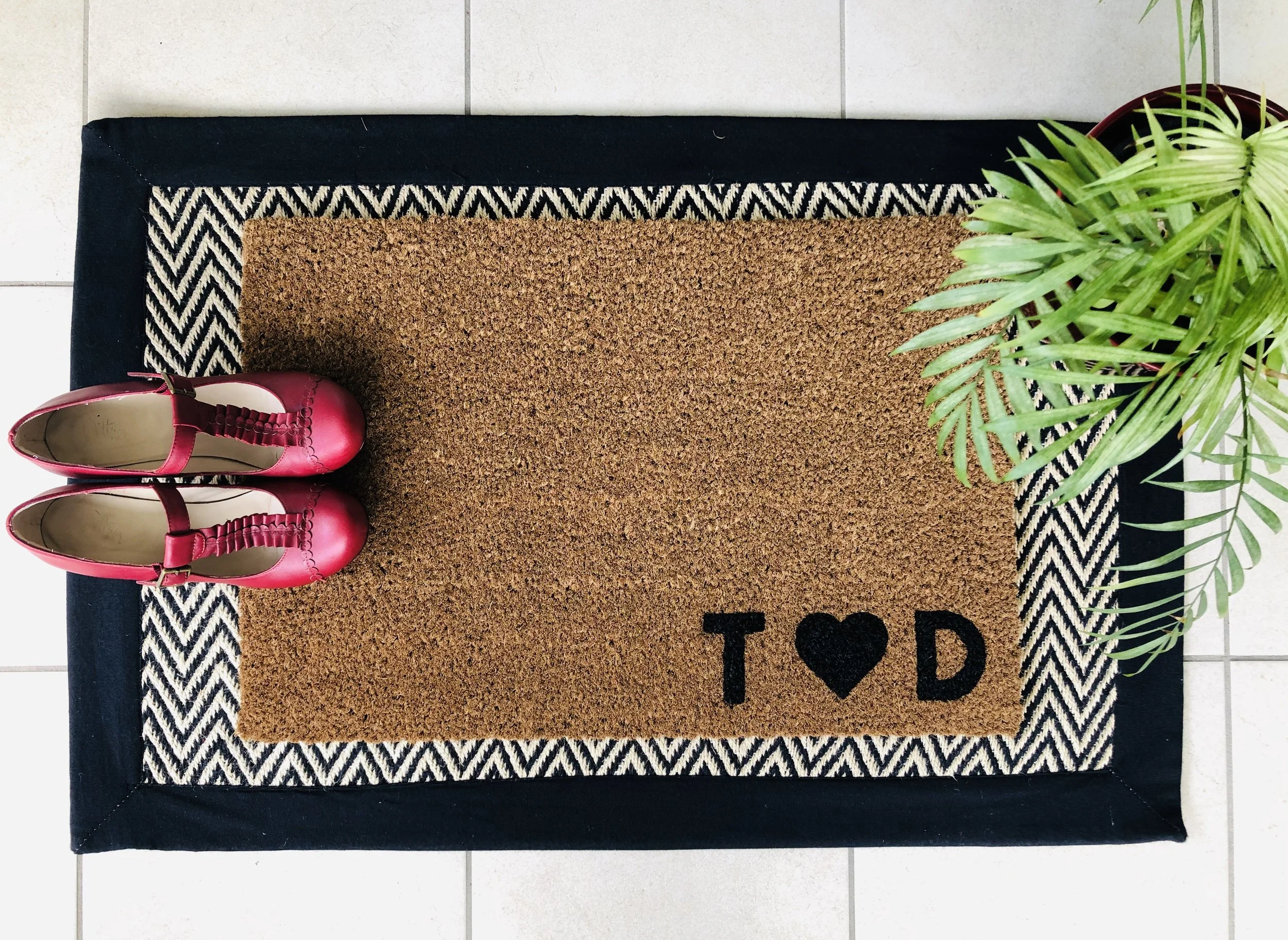 A coir doormat with black personalisation on the bottom right of the mat. This one reads T love heart D