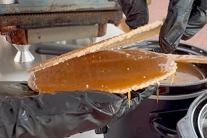 Fresh Dutch stroopwafel held open with warm caramel just before the two layers are pressed together