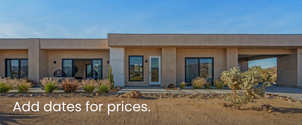 Modern single-story house with desert landscaping, including cacti and drought-tolerant plants, under a clear blue sky.