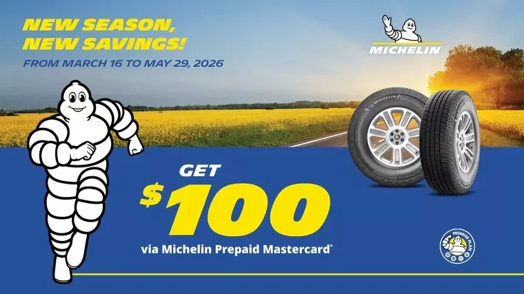 Michelin advertisement offering $100 via prepaid Mastercard from March 16 to May 29, 2026, featuring Michelin tire images, the Michelin mascot, and a rural background with fields and a road.
