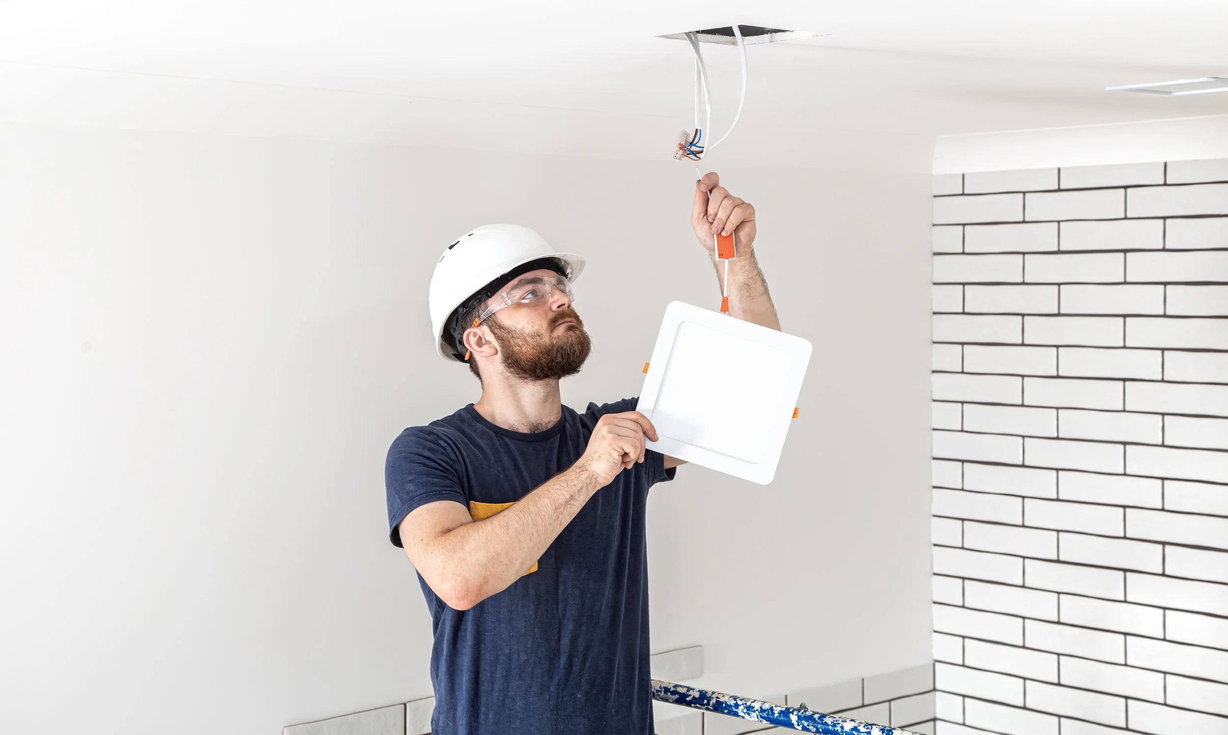 electrician-builder-with-beard-worker-white-helmet-work-installation-lamps-height-professional-overalls-with-drill-repair-site.jpg