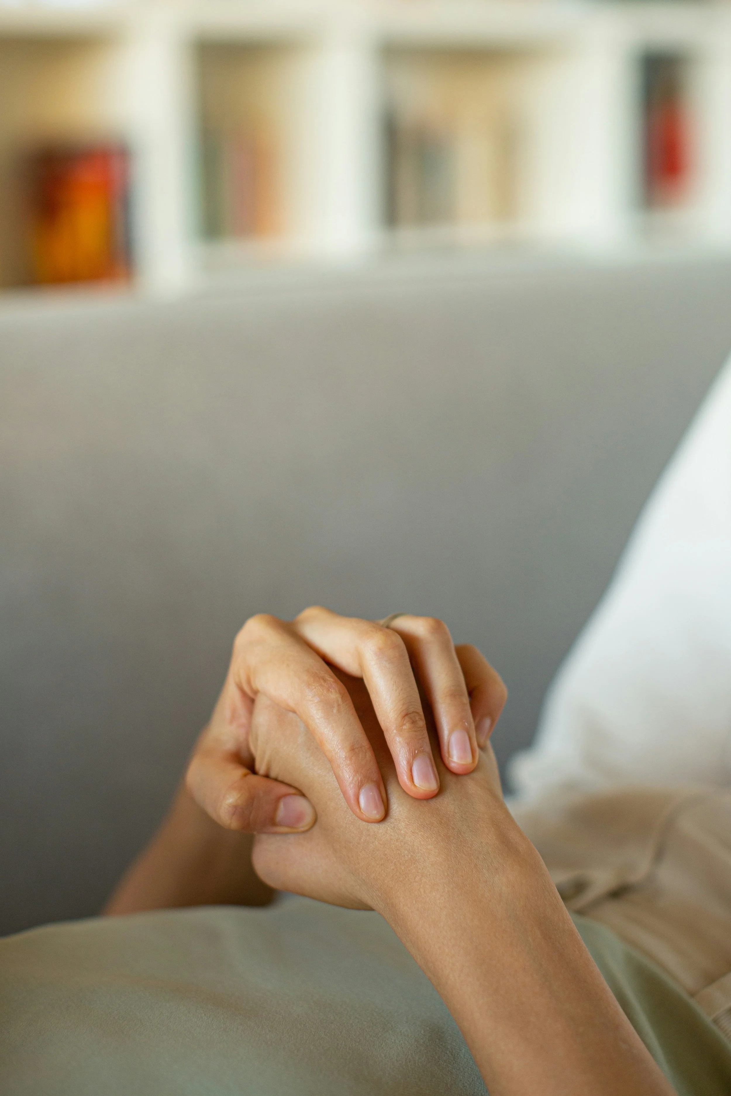 Hands gently clasped in a moment of reflection, symbolising comfort, connection, and emotional healing in therapy.