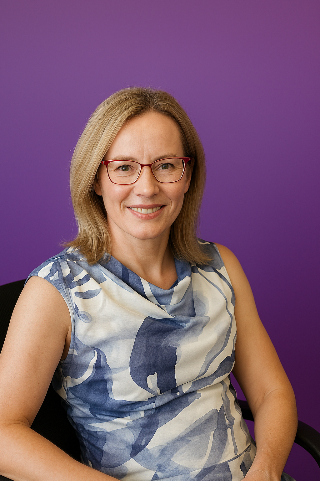 Professional psychologist smiling warmly against a purple background, representing a supportive, trauma-informed, and neurodiversity-affirming approach to therapy in South Australia.