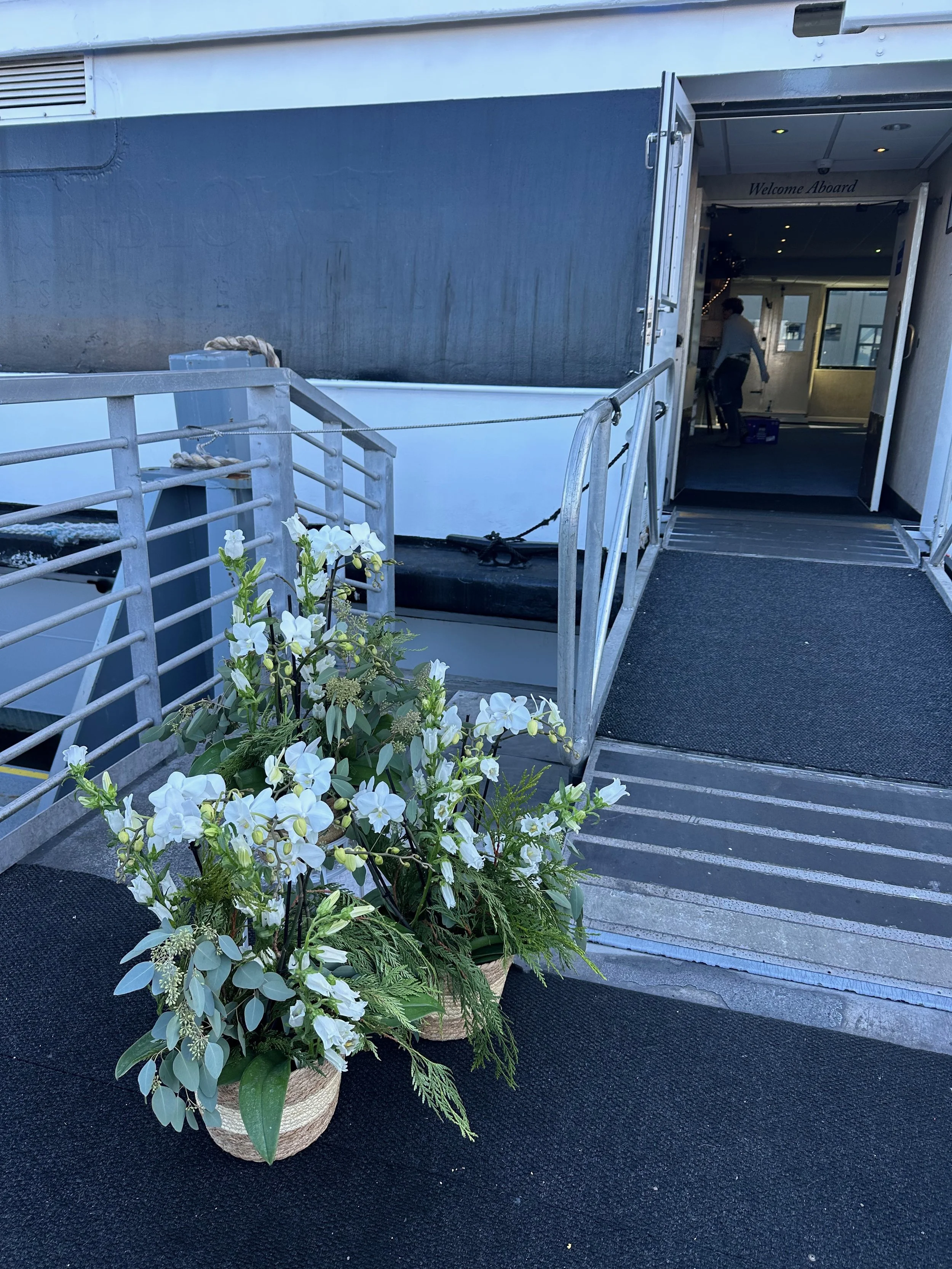 Entrance to a boat with potted white flowers near the ramp.