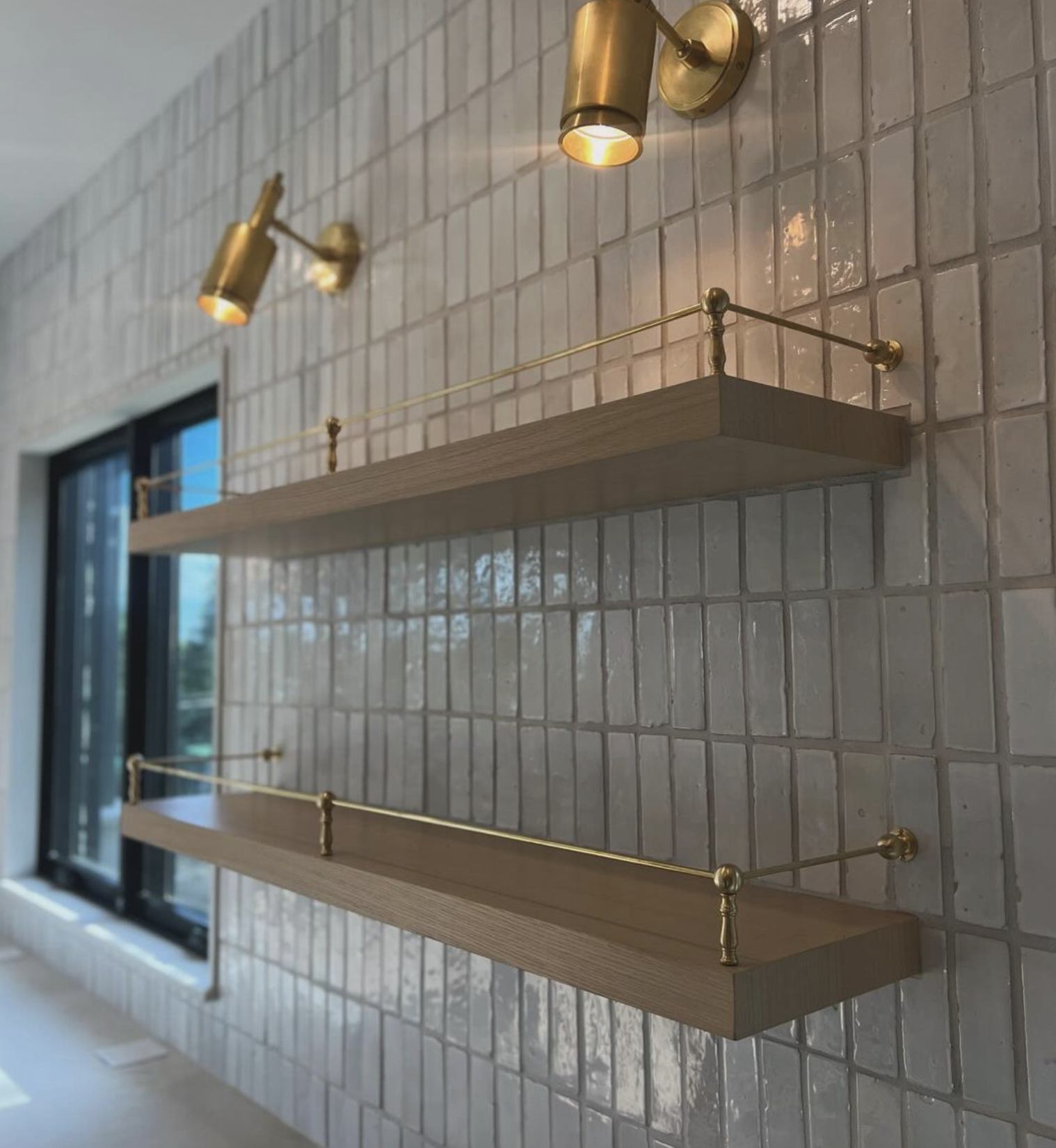 kitchen floating shelves with brass plate rails, zellige tiles, and gold sconces in a high end home