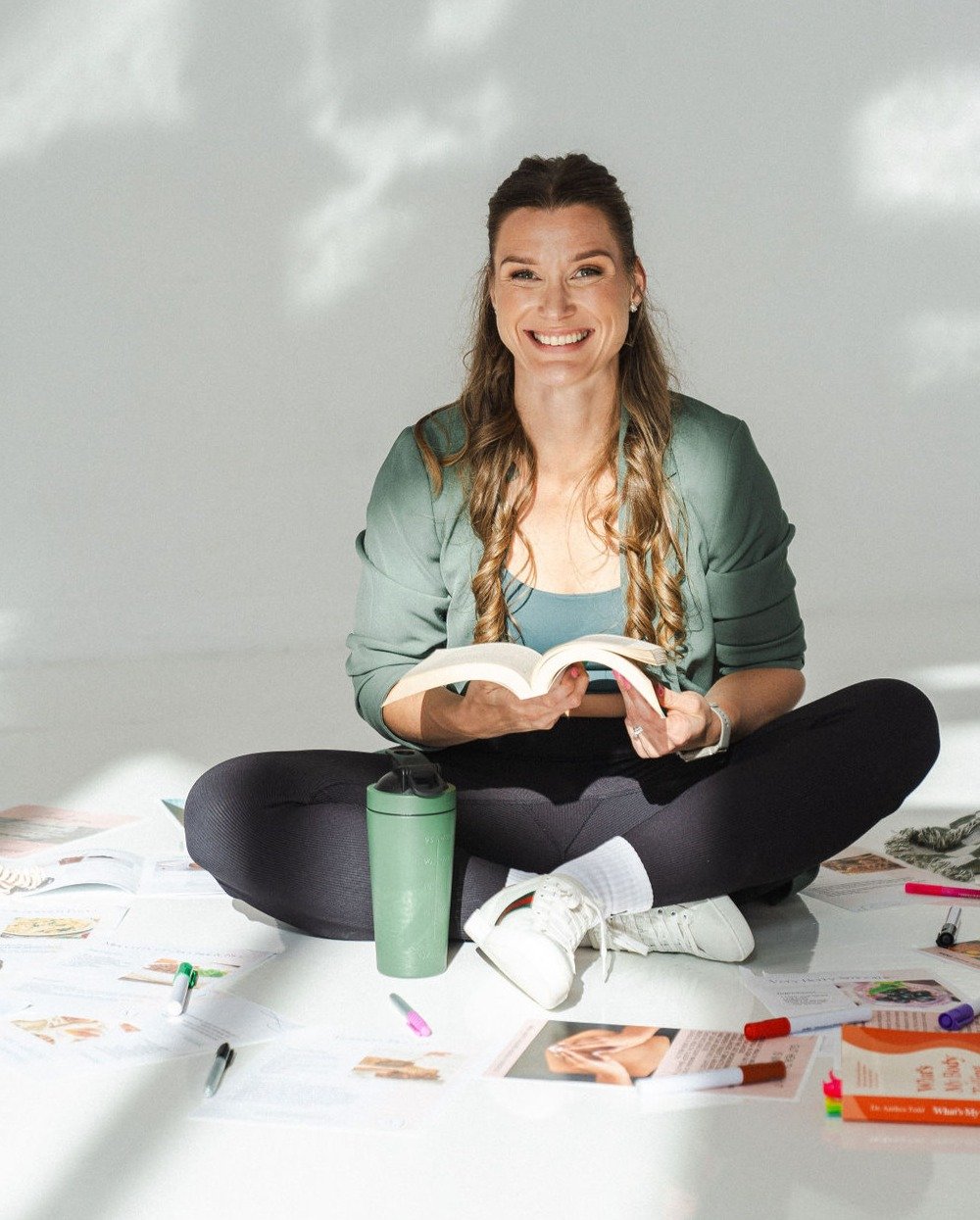 Anna sitting cross leg on the floor reading recipes