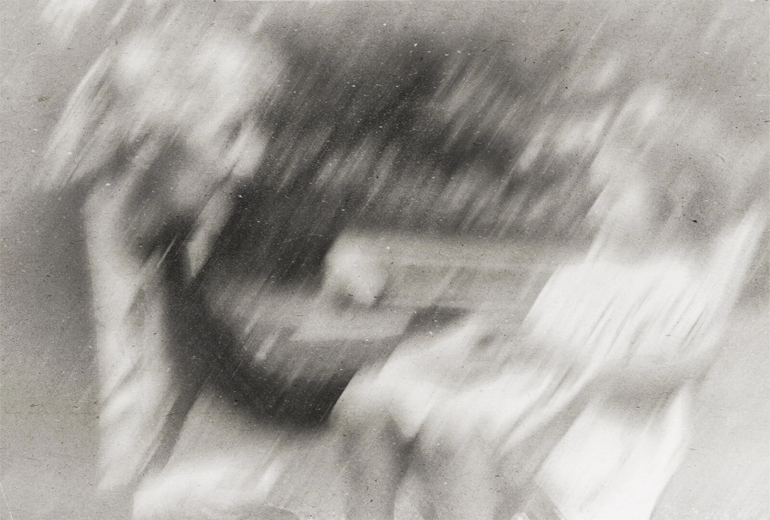 A blurry, black-and-white photo of a person playing a netted instrument, possibly a guitar, in a room with bookshelves and a desk.