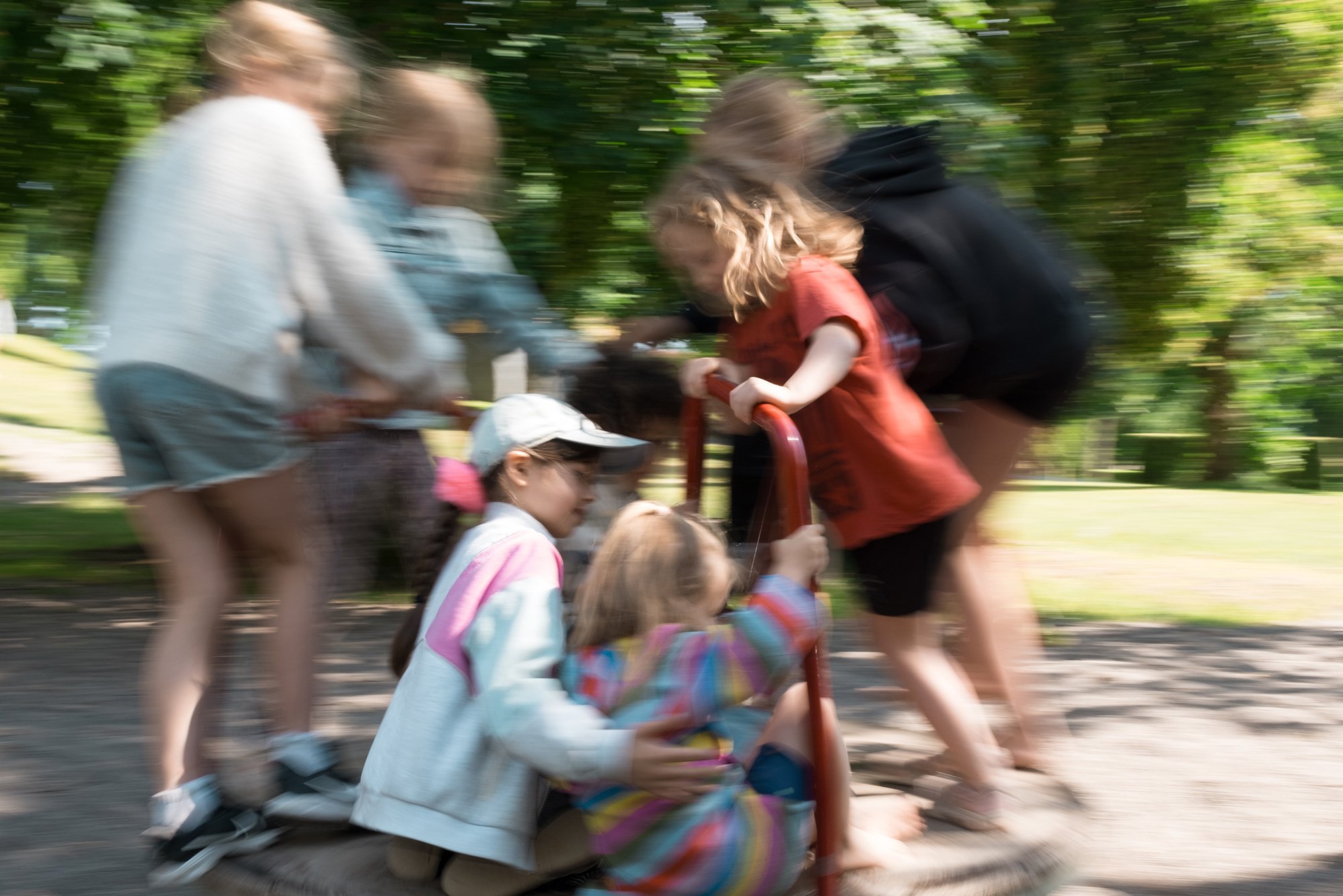 Children playing on a merry-go-round in a park.