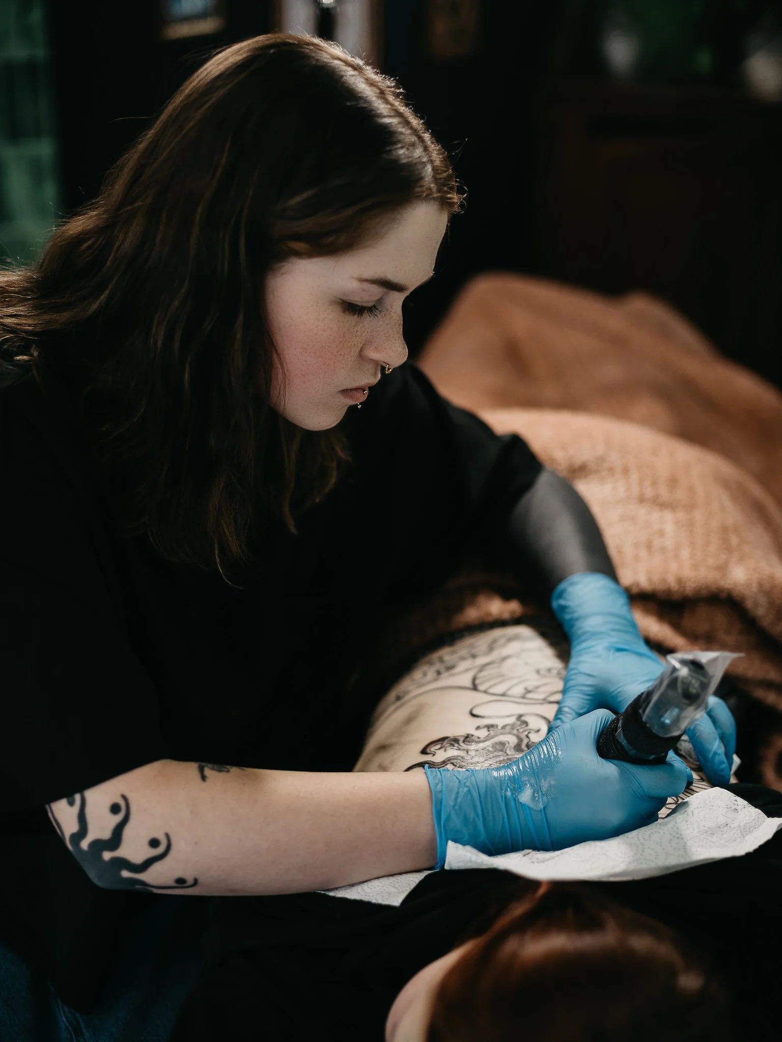 Tattoo artist ink designing on client's side tattoo in a tattoo studio.