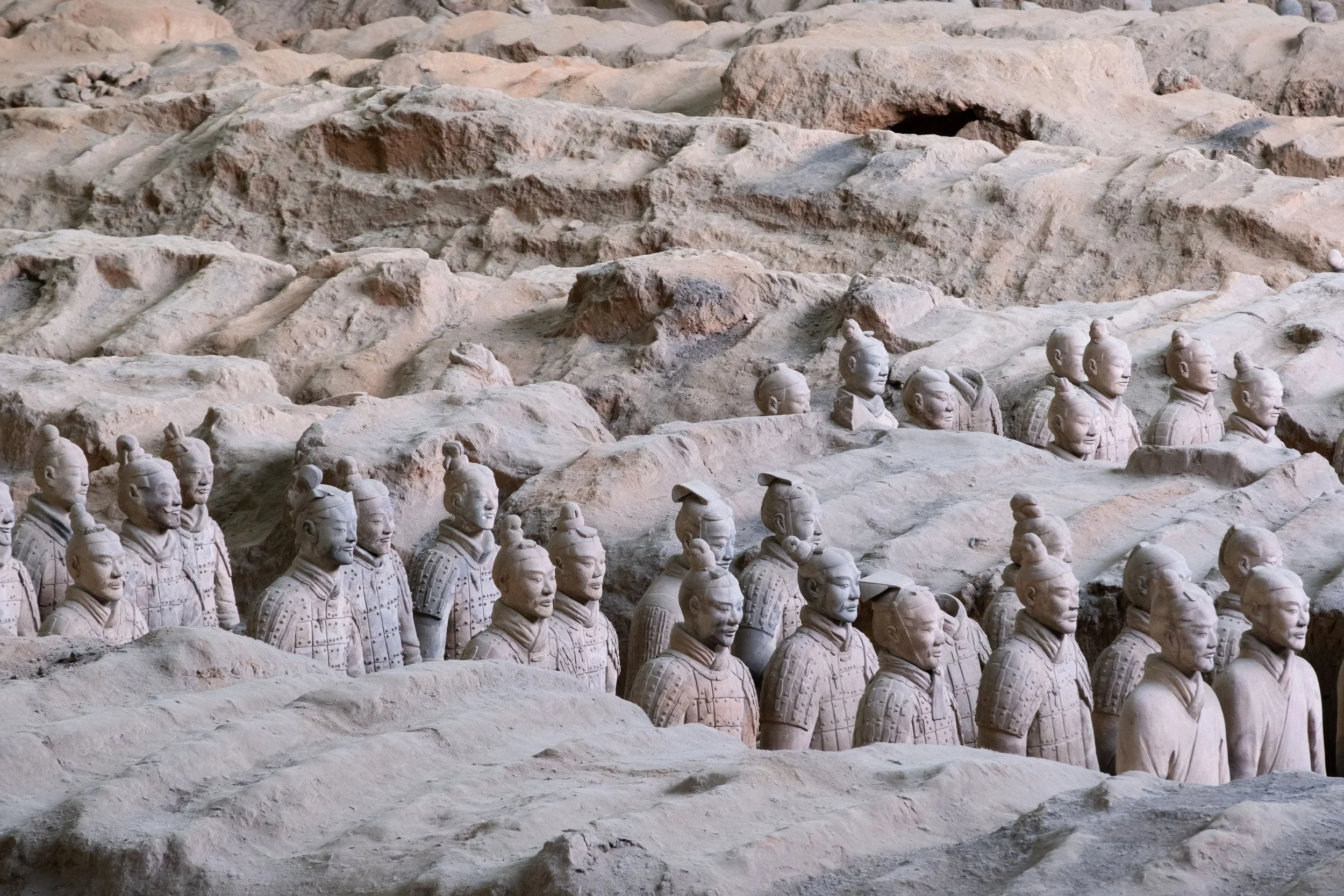 Terracotta warriors standing in formation on a rocky terrain in China.