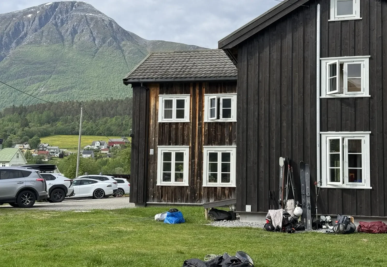 Black wooden house with white-framed windows below the mountains
