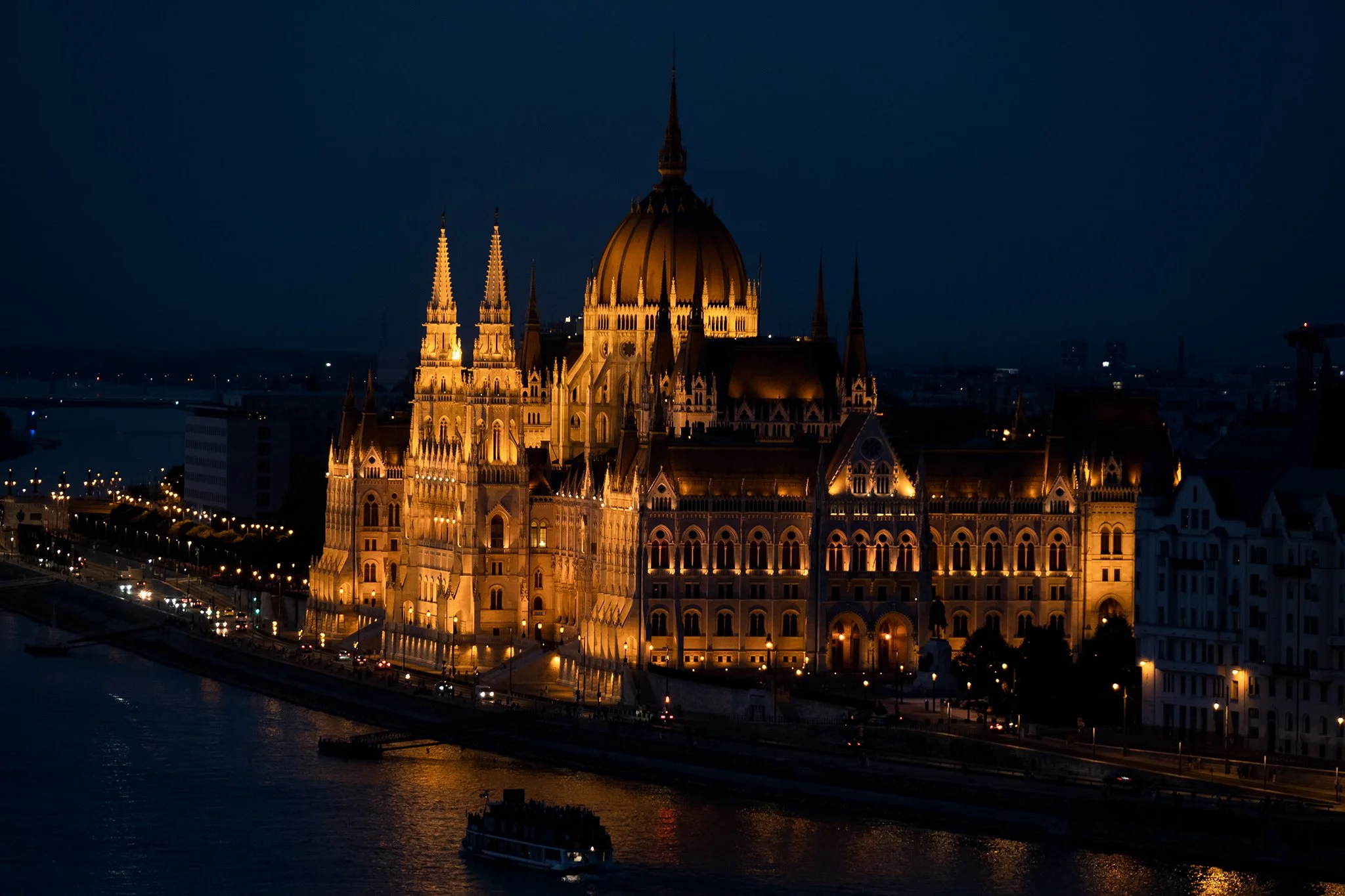 Nighttime view of the illuminated Hungarian Parliament Building along the Danube River in Budapest.