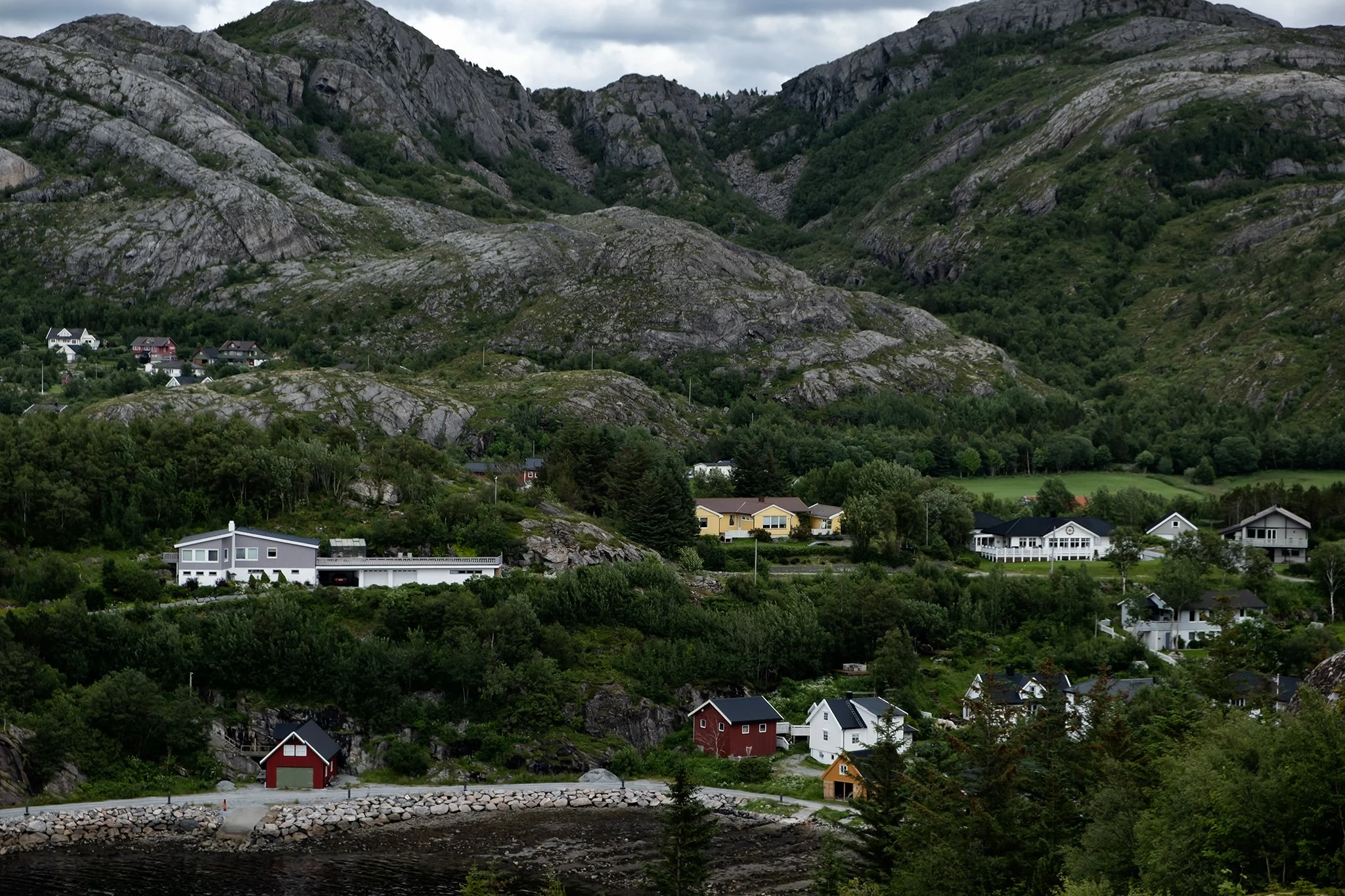 Residential houses at the base of large, rocky green mountains.