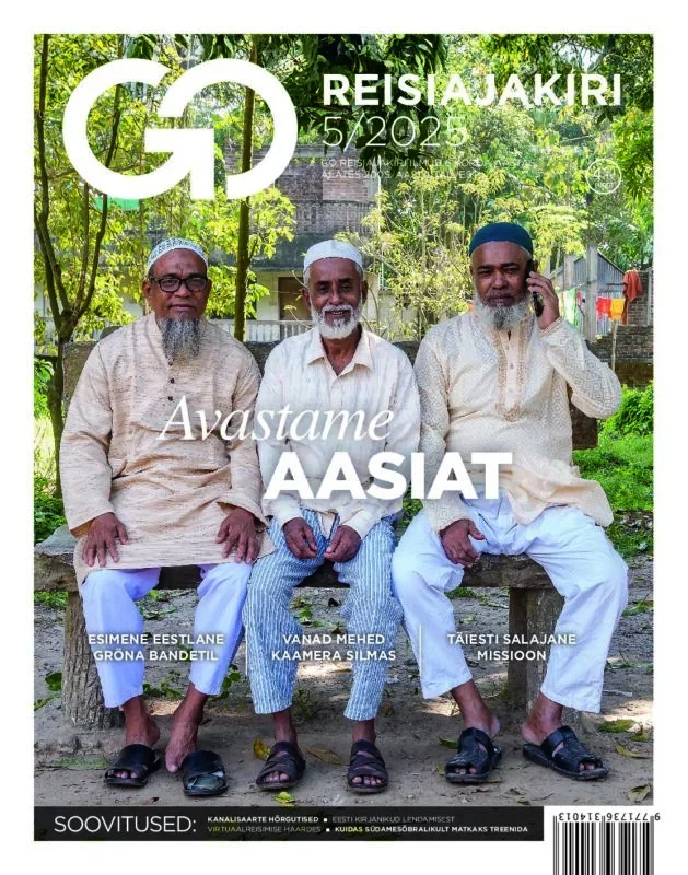 Three elderly men sit on a wooden bench outdoors in traditional attire, with green trees and a building in the background. The magazine cover features a large GO logo, the title 'REISIJAKIRI,' and the issue date '5/2023.' The main headline reads 'Avastame AASIAT,' and additional text mentions names and organizations.