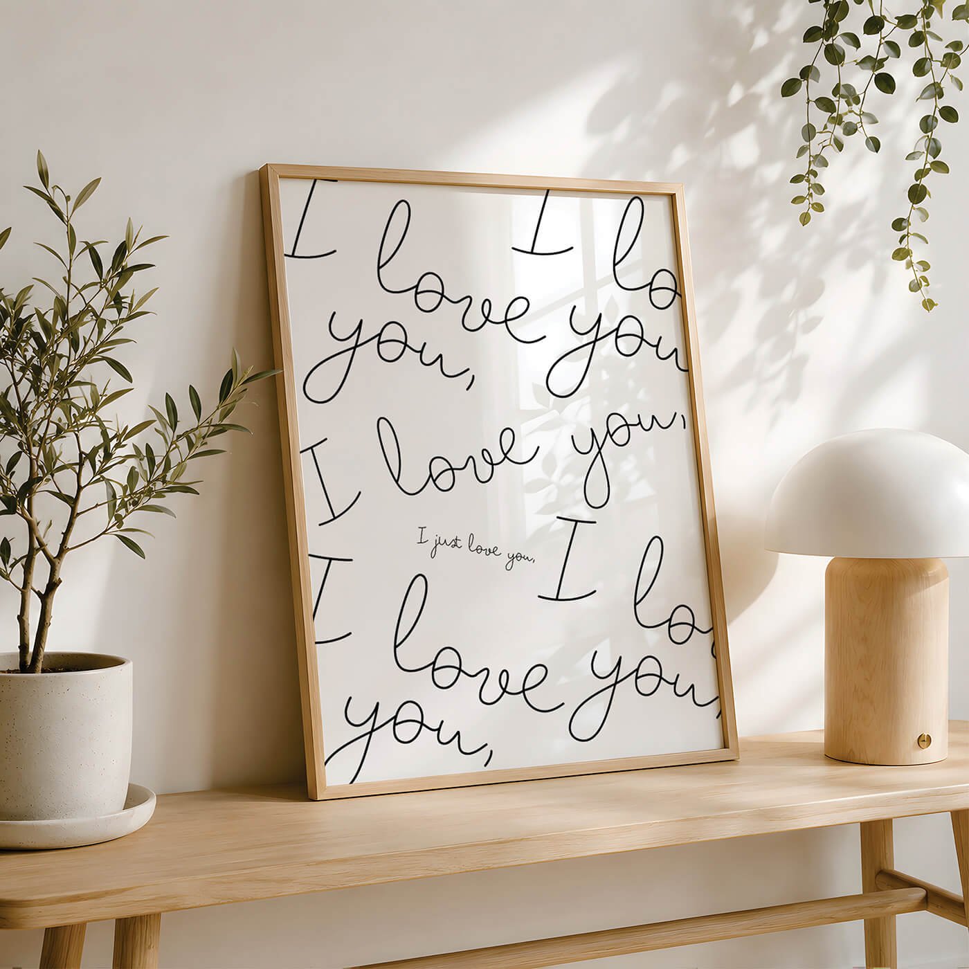 Black and White I Just Love You Print framed in wood and styled on a contemporary sideboard with a modern lamp and plant.